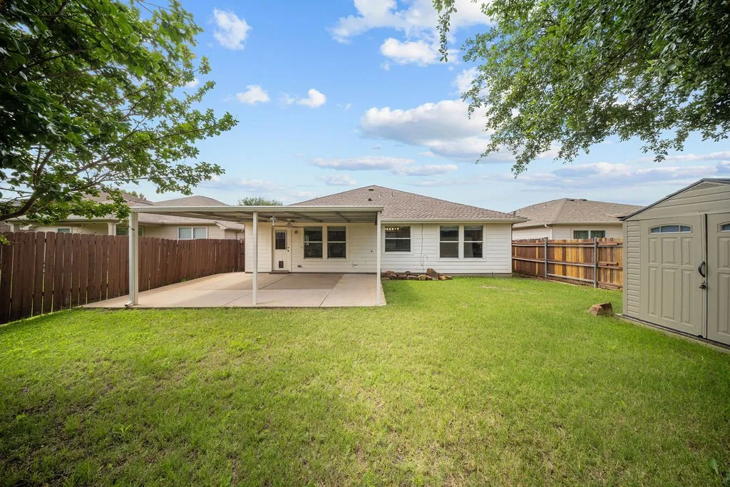 Expansive backyard featuring a covered patio, a storage shed, and a privacy fence