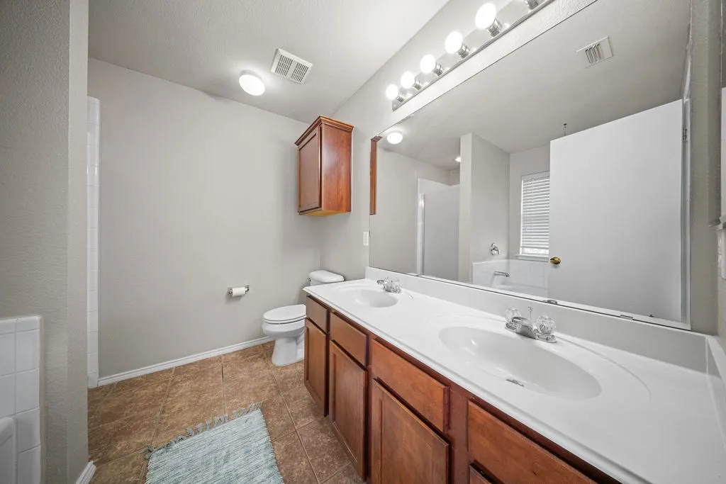 Bathroom featuring a dual vanity with integrated sinks, wood cabinetry, and a large wall-mounted mirror