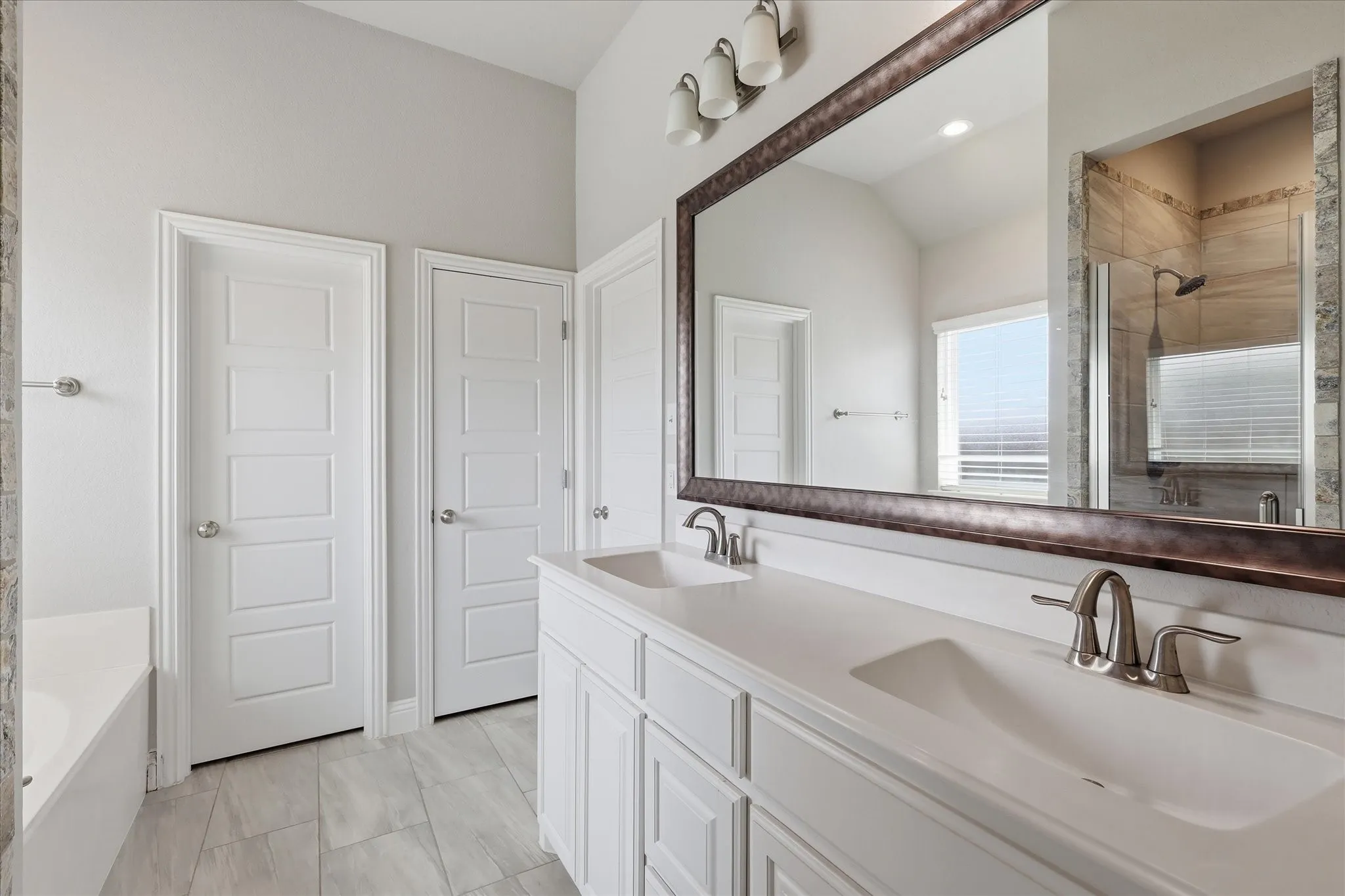 Retreat to the spacious primary bath featuring dual vanities, a relaxing soaking tub, and a separate walk-in shower designed for both comfort and convenience.