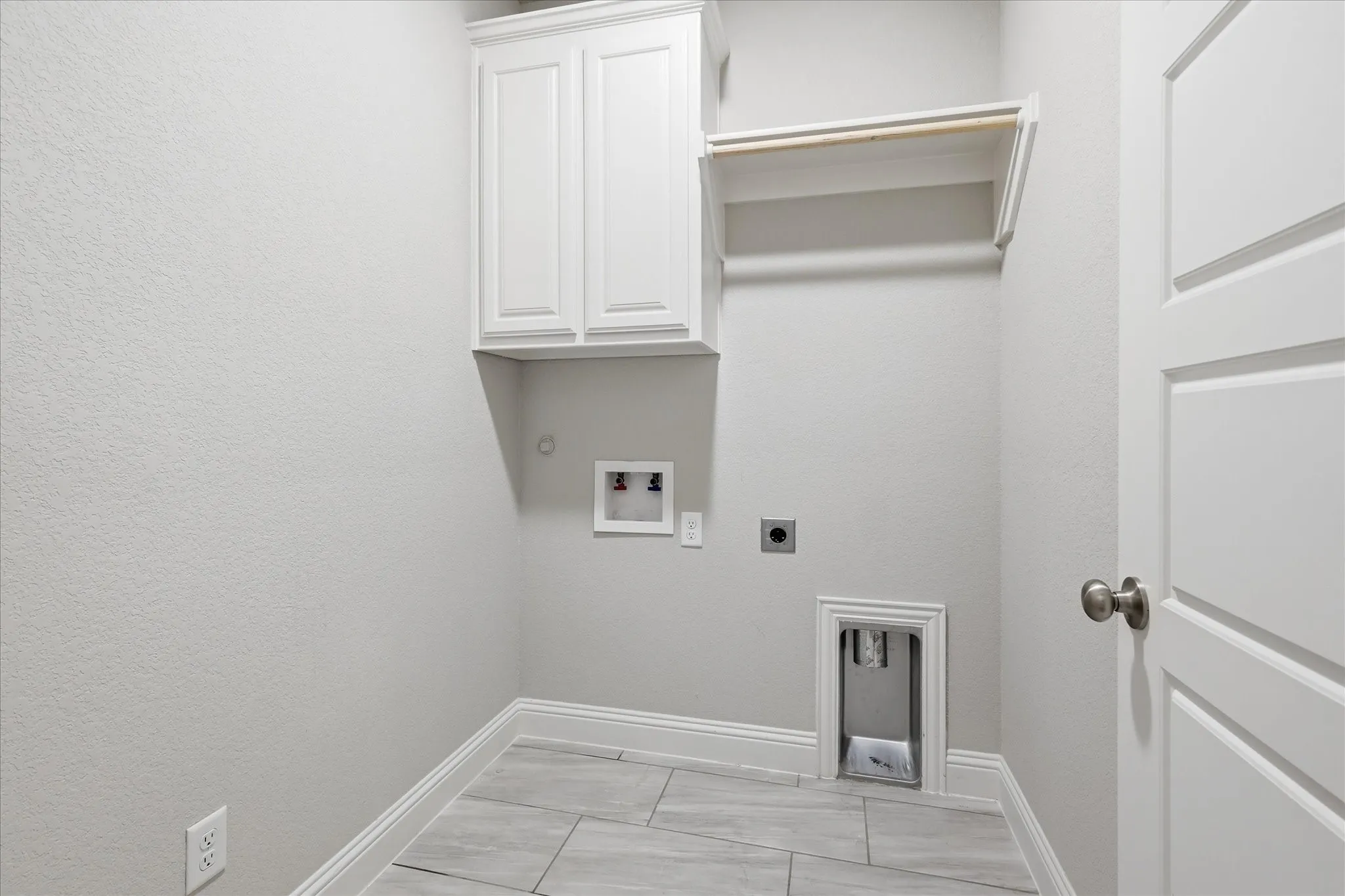 Well-appointed utility room featuring built-in cabinetry, shelving, and space for a full-size washer and dryer, making everyday chores a breeze.