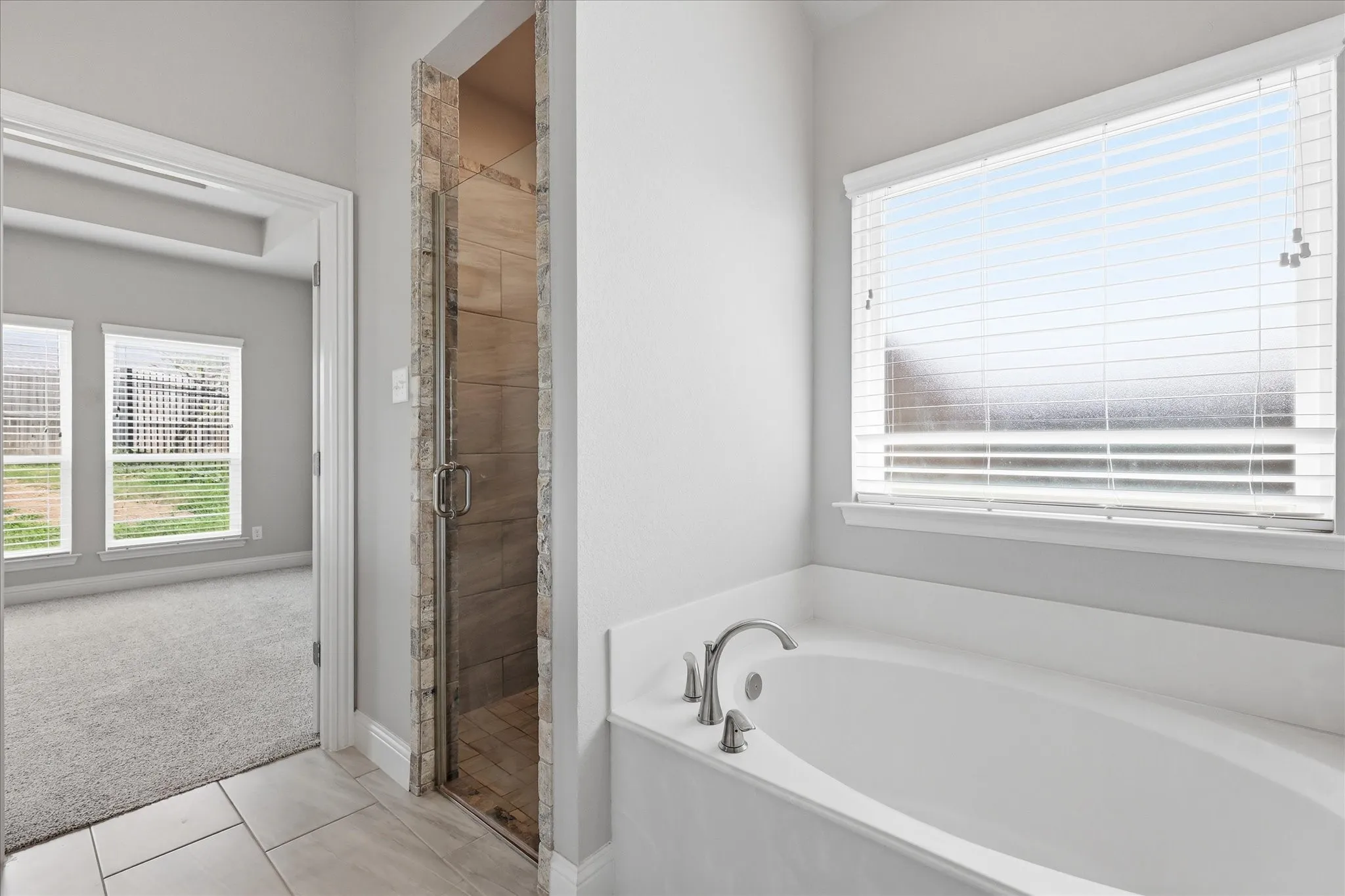 Escape to the spa-like primary bath featuring a relaxing soaking tub, separate walk-in shower, and elegant finishes designed for comfort and relaxation.