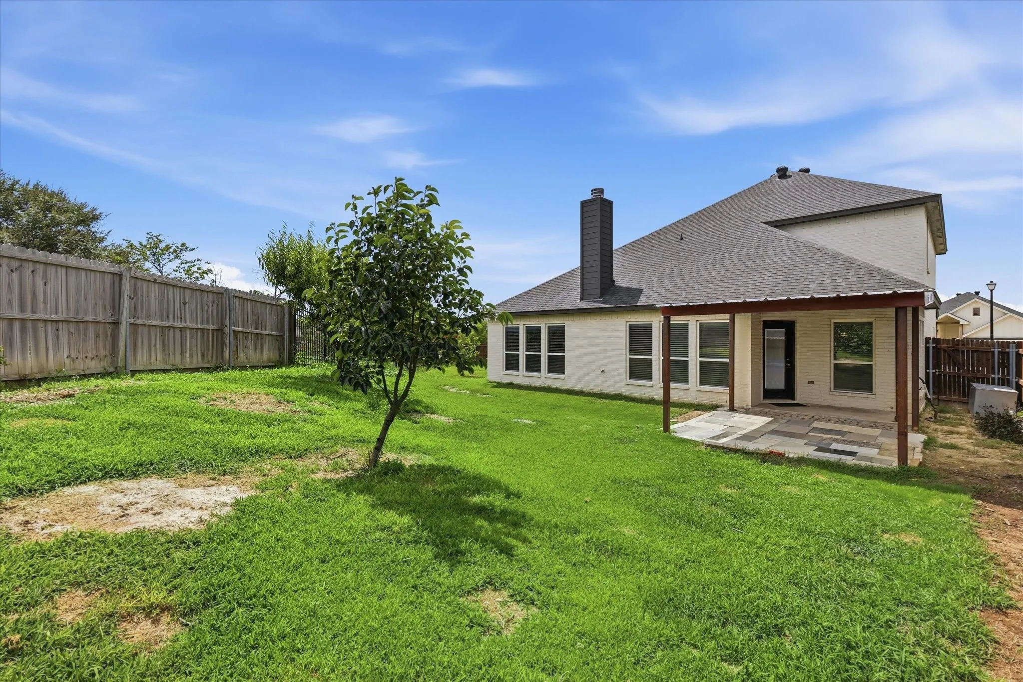 Large backyard with a covered patio and plenty of green space for pets, play, gardening, or enjoying the Texas evenings