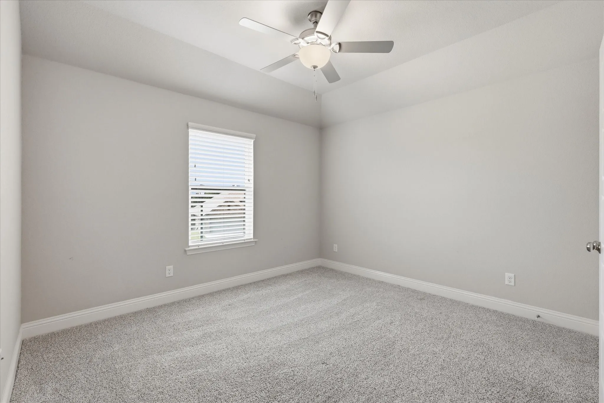 Carpeted room featuring a single window with blinds, a ceiling fan with integrated lighting, and neutral wall paint