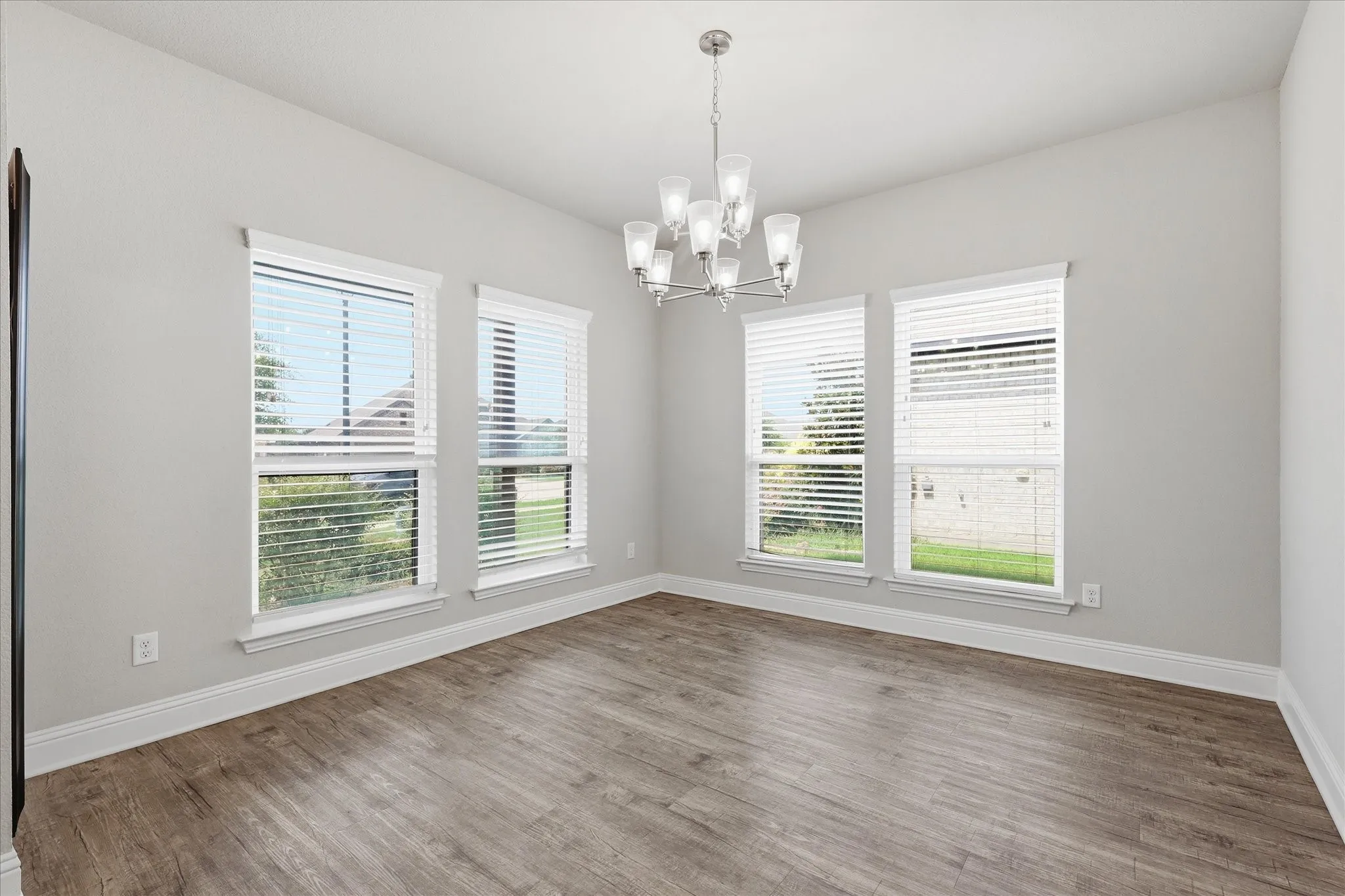 Sun-filled dining room featuring expansive windows, elegant lighting, and plenty of space for gathering with family and friends.