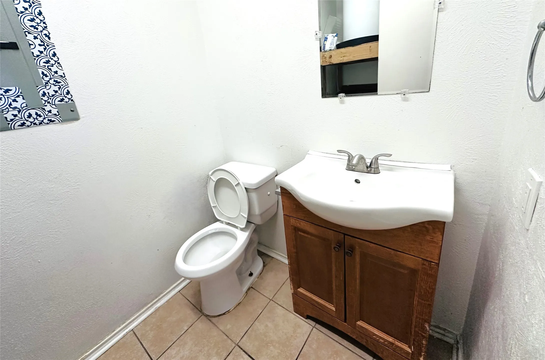Bathroom featuring a pedestal toilet, ceramic tile flooring, and a wood-finish vanity with an integrated sink