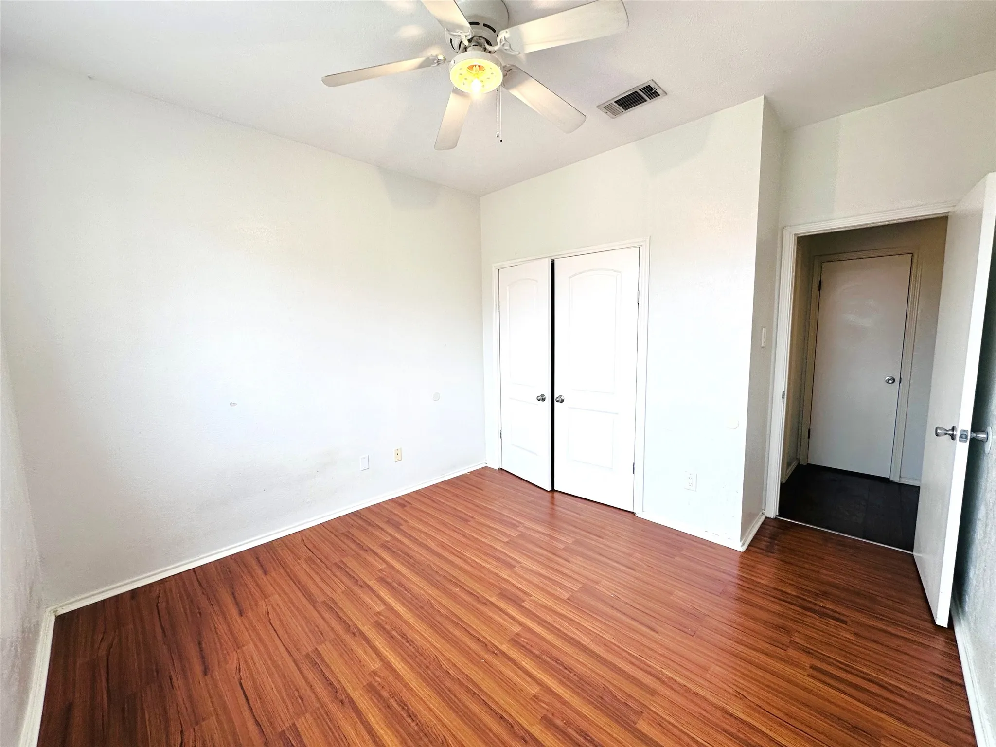 Room featuring wood-finish flooring, a ceiling fan, and white walls