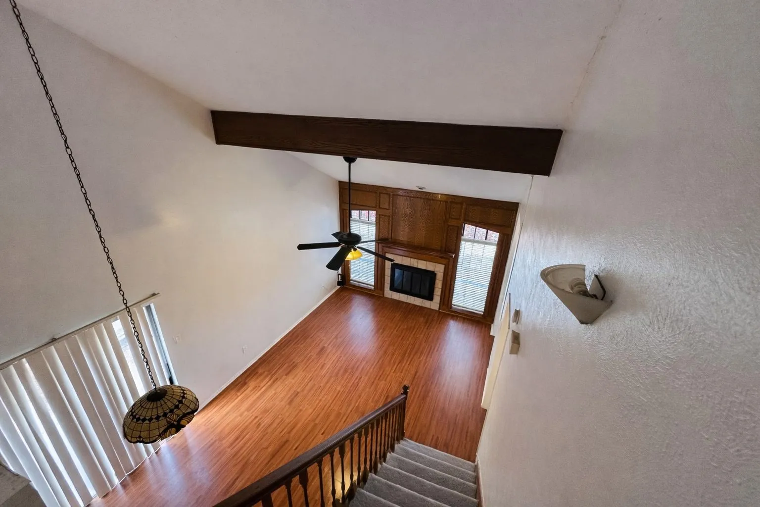 Living area featuring high vaulted ceilings, a prominent exposed beam, a ceiling fan, and wood-finish flooring