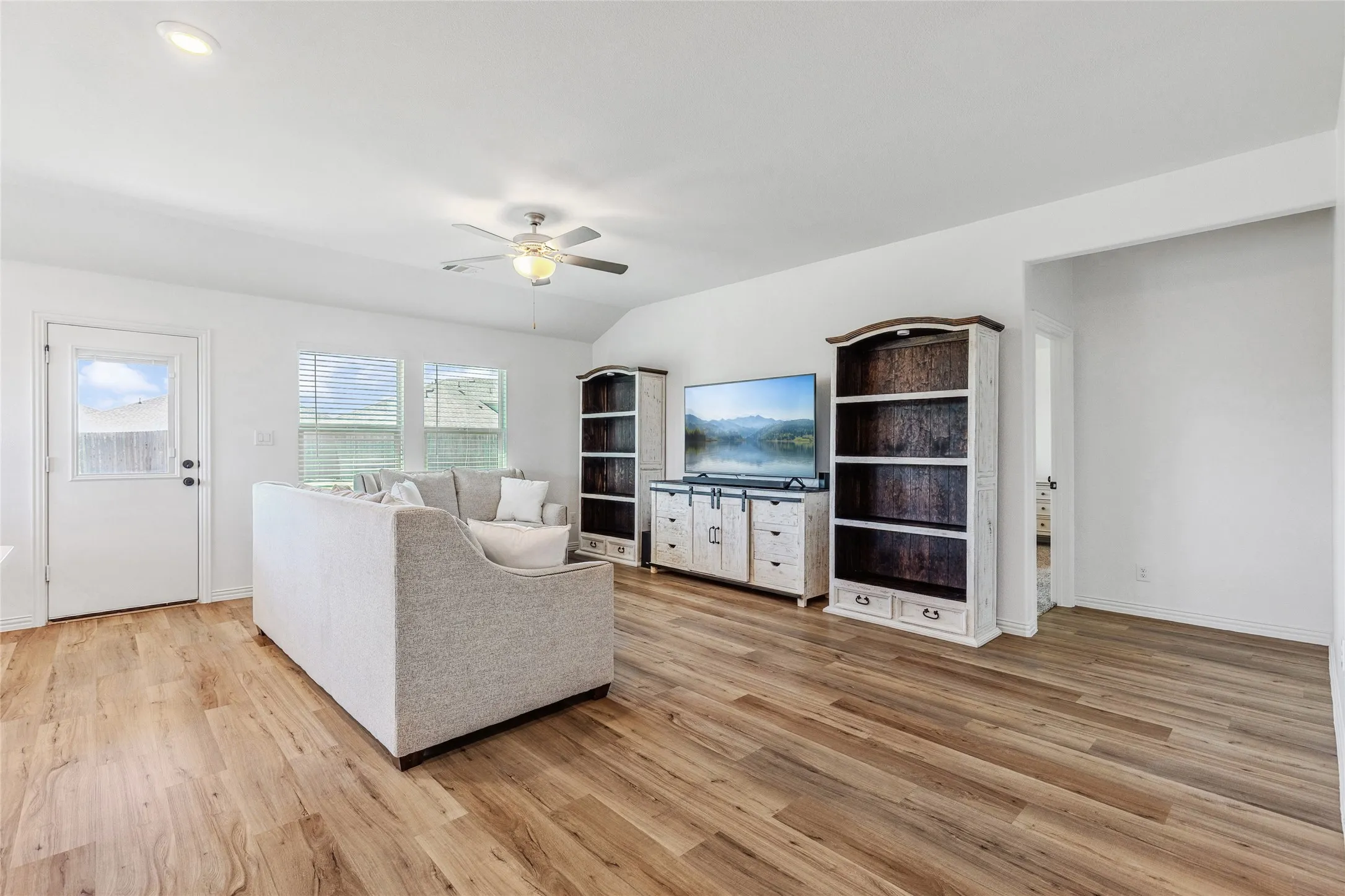 Open-concept living area featuring wood-finish flooring, vaulted ceilings, and recessed lighting