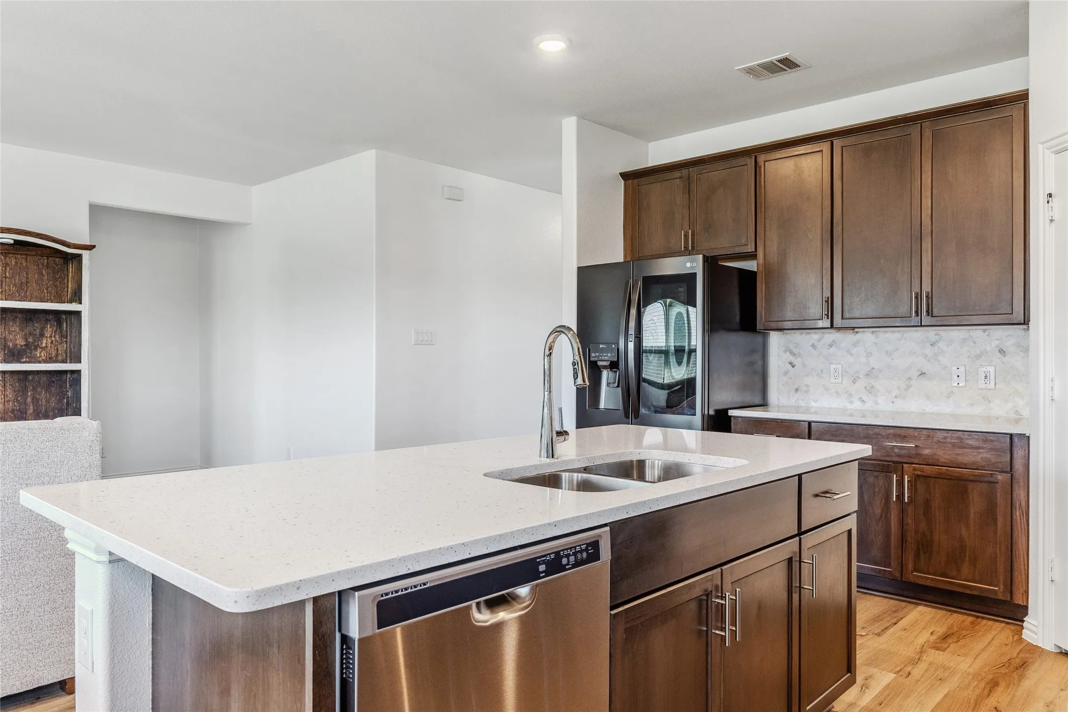 Kitchen island with a light-toned countertop, double basin stainless steel sink, and a modern pull-down faucet