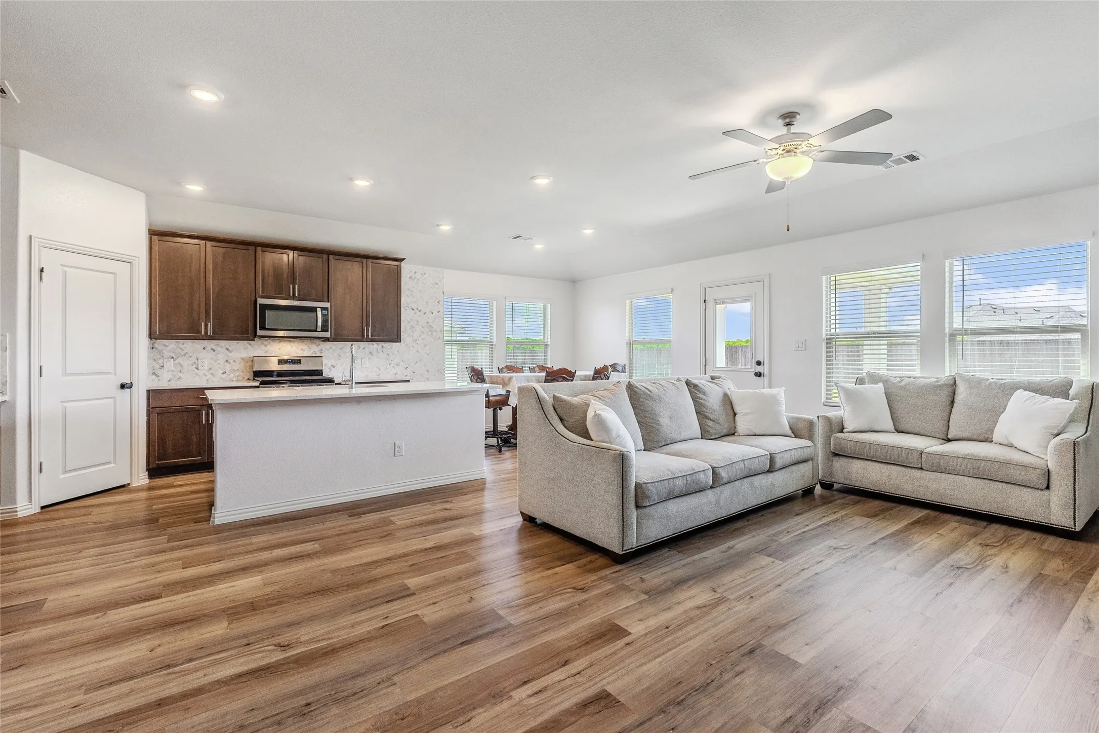 Open-concept living area with wood-finish flooring, recessed lighting, and a ceiling fan