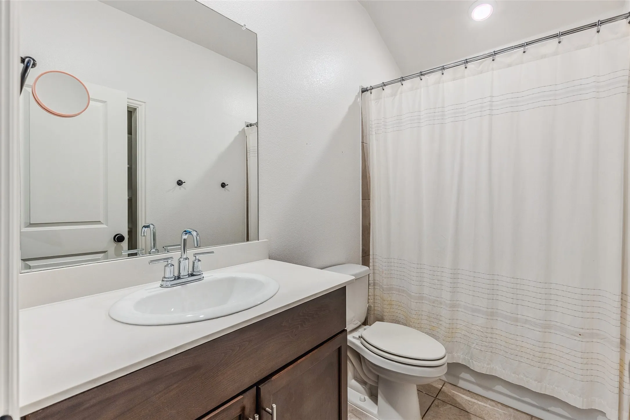 Bathroom featuring a white oval undermount sink, chrome faucet, and a large vanity mirror