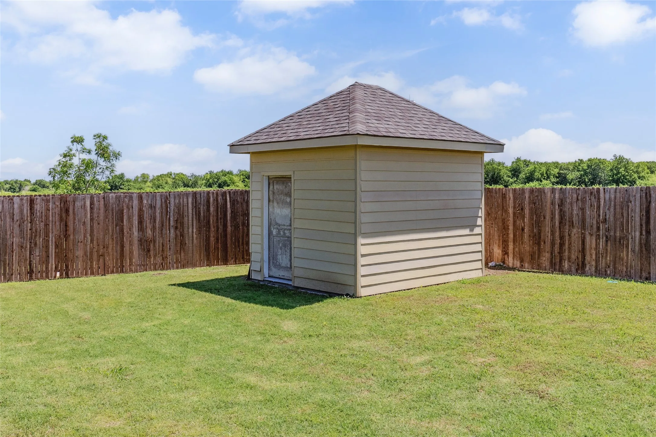 Detached storage shed featuring horizontal siding and an asphalt shingle roof