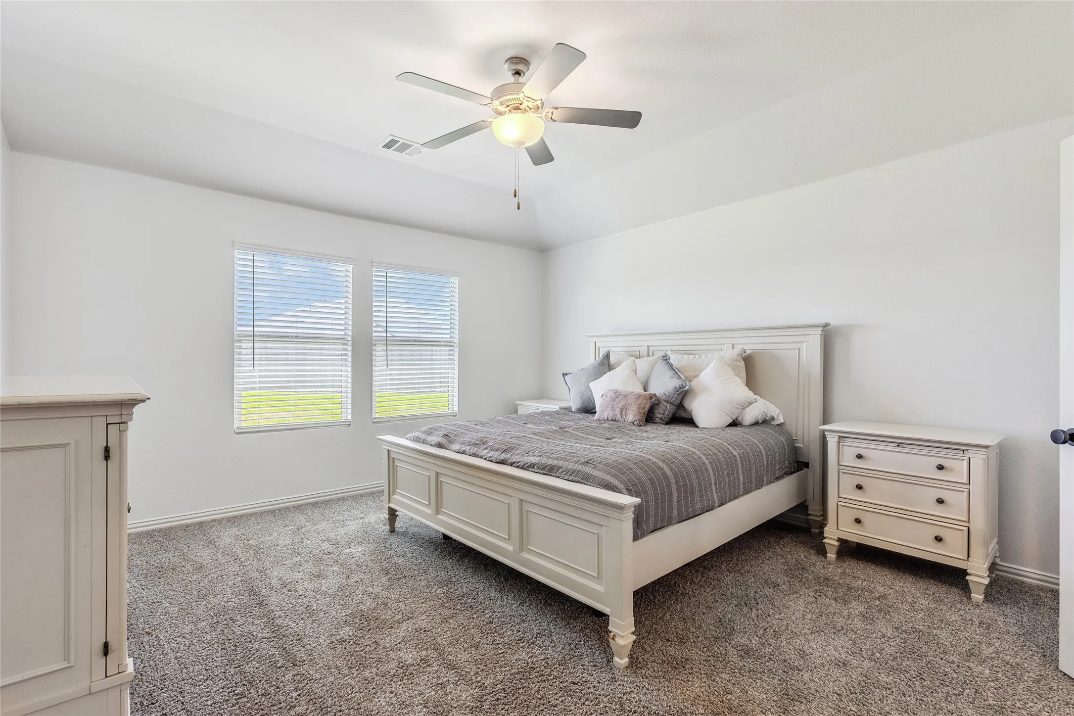 Carpeted interior space featuring a vaulted ceiling with a flush-mount ceiling fan