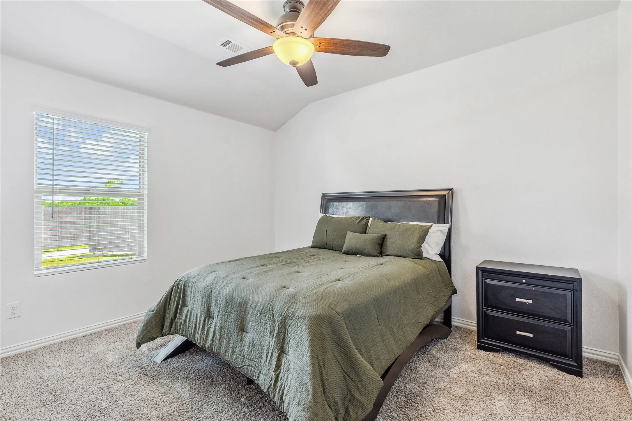 Carpeted room featuring a window with horizontal blinds, a ceiling fan with light fixture, and vaulted ceilings