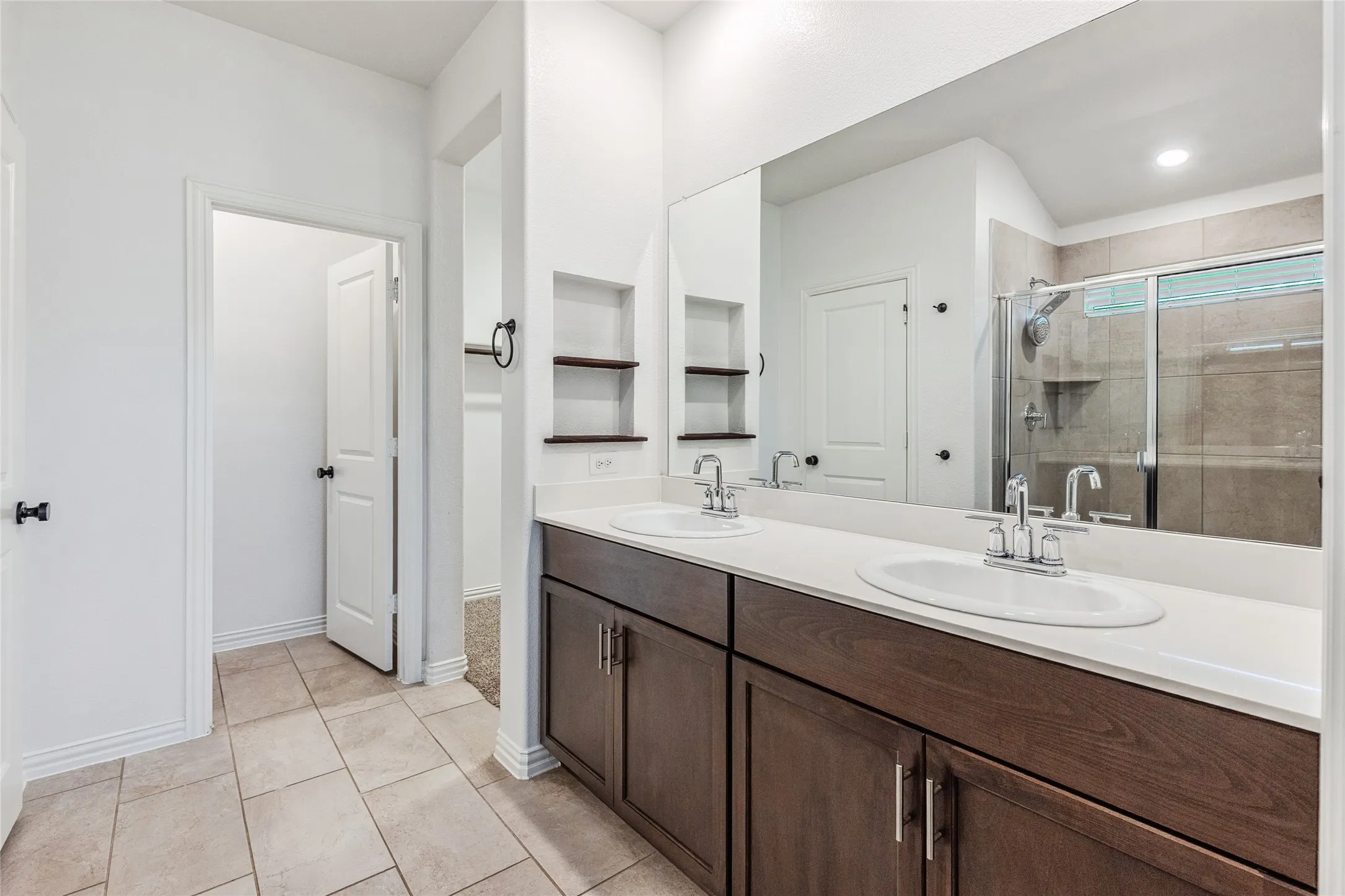 Dual vanity featuring integrated sinks, chrome fixtures, and a spacious wall-mounted mirror