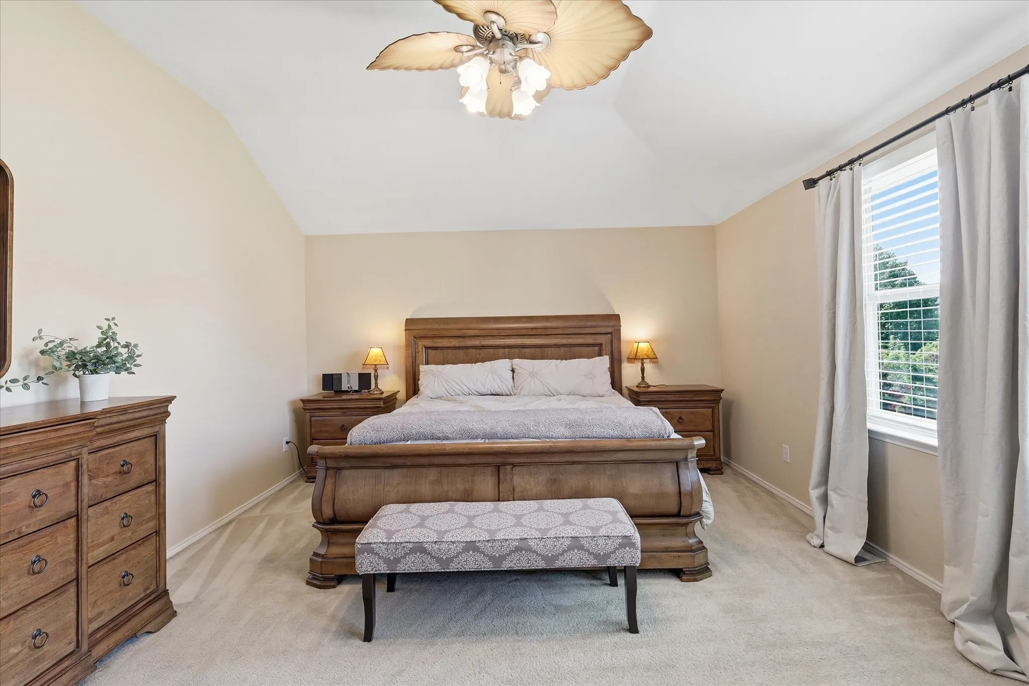 Room featuring vaulted ceilings with a ceiling fan, wall of windows with blinds and drapes, and light-toned carpeting