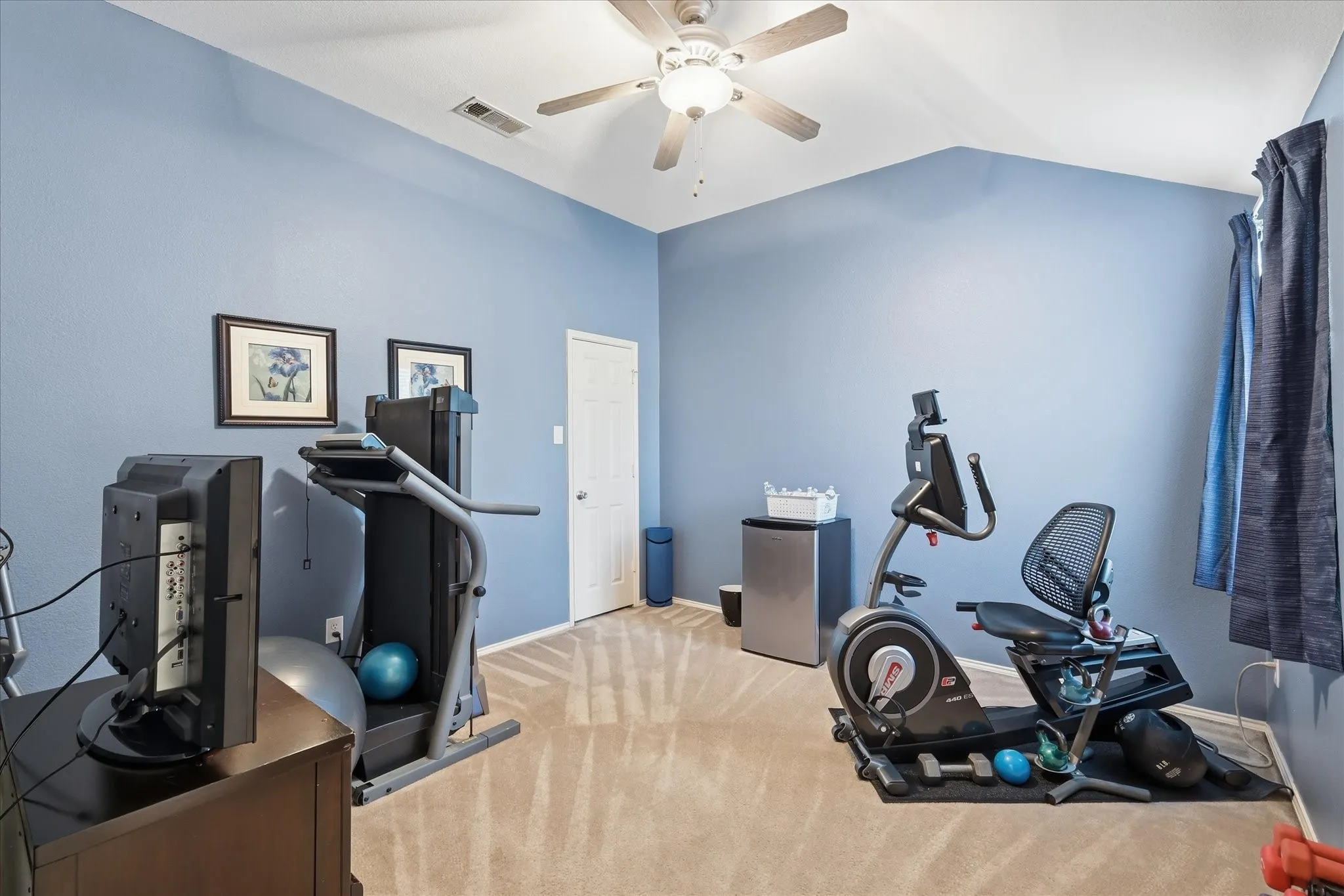 Secondary bedroom featuring sloped ceilings, ceiling fan with integrated lighting, and carpet flooring - private with walkin closet
