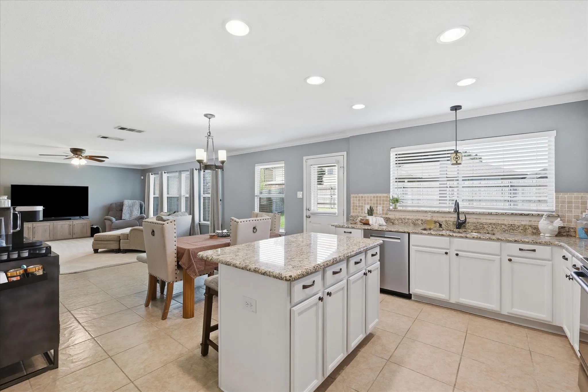 Kitchen featuring a central island with countertop, tile flooring, white cabinetry with dark hardware, and a tile backsplash