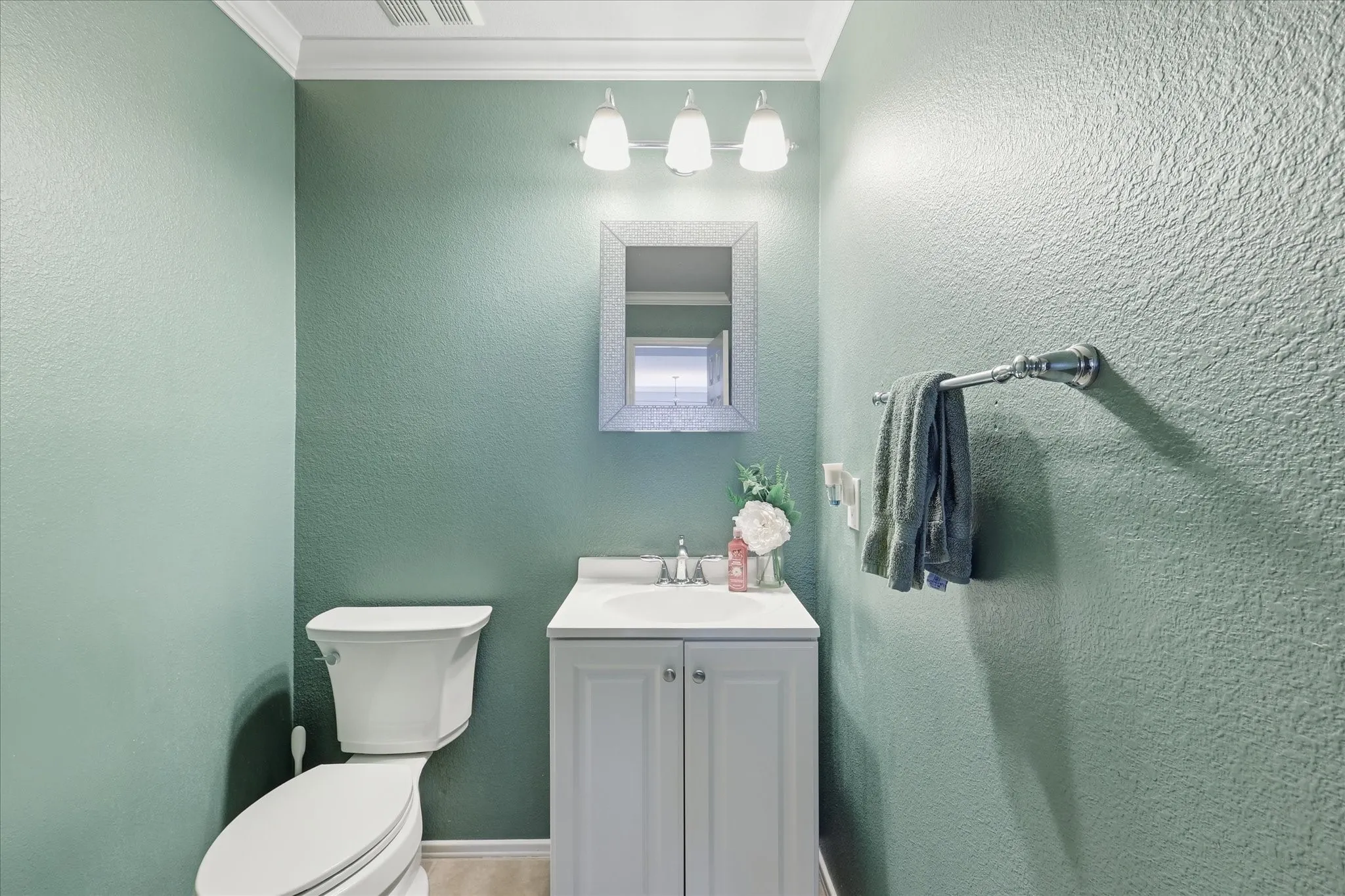 Powder room featuring a white vanity with integrated sink, chrome faucet, and a wall-mounted mirror