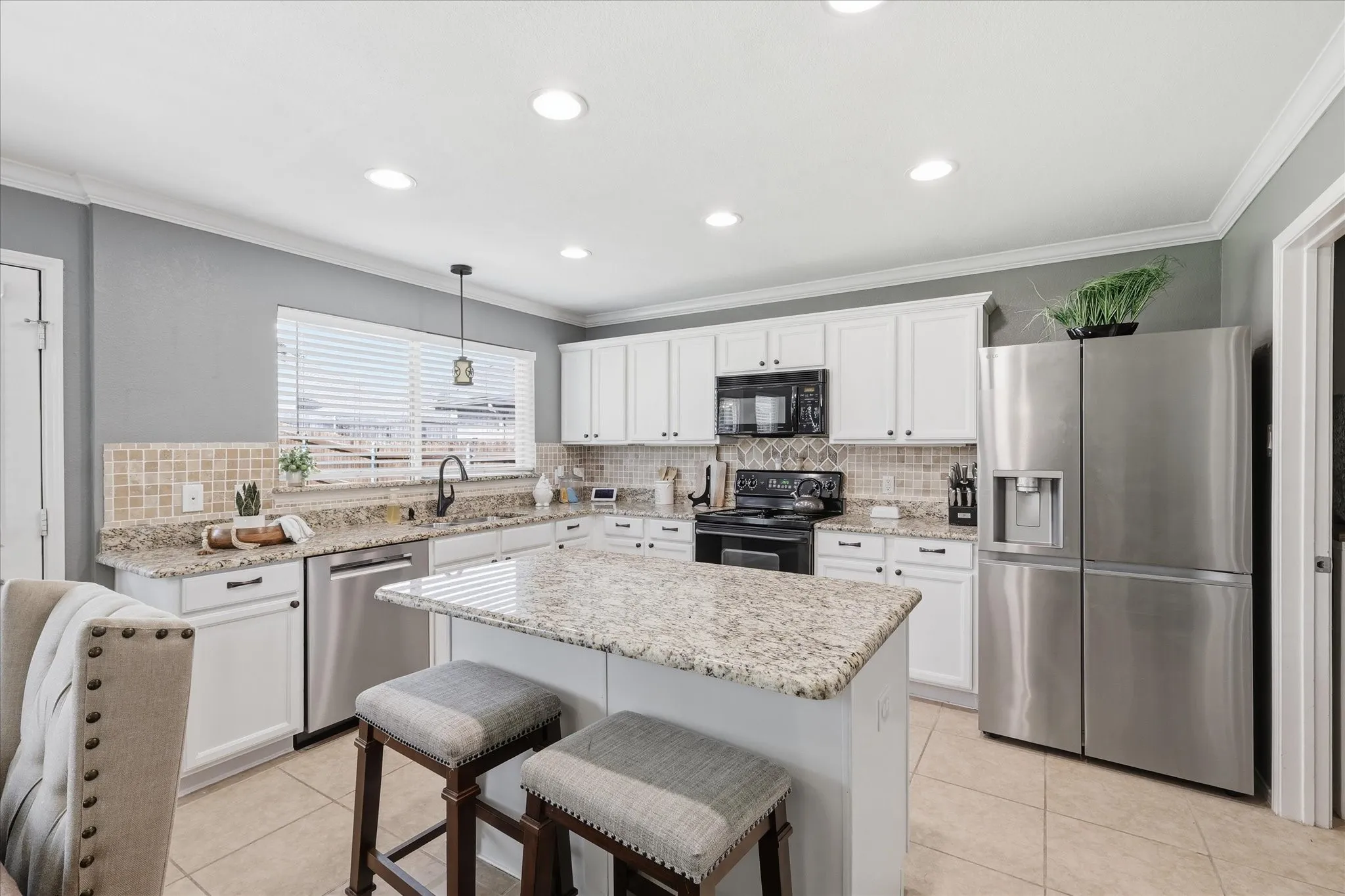 Kitchen featuring white cabinetry, granite countertops, stainless steel appliances, a tiled backsplash, and recessed lighting