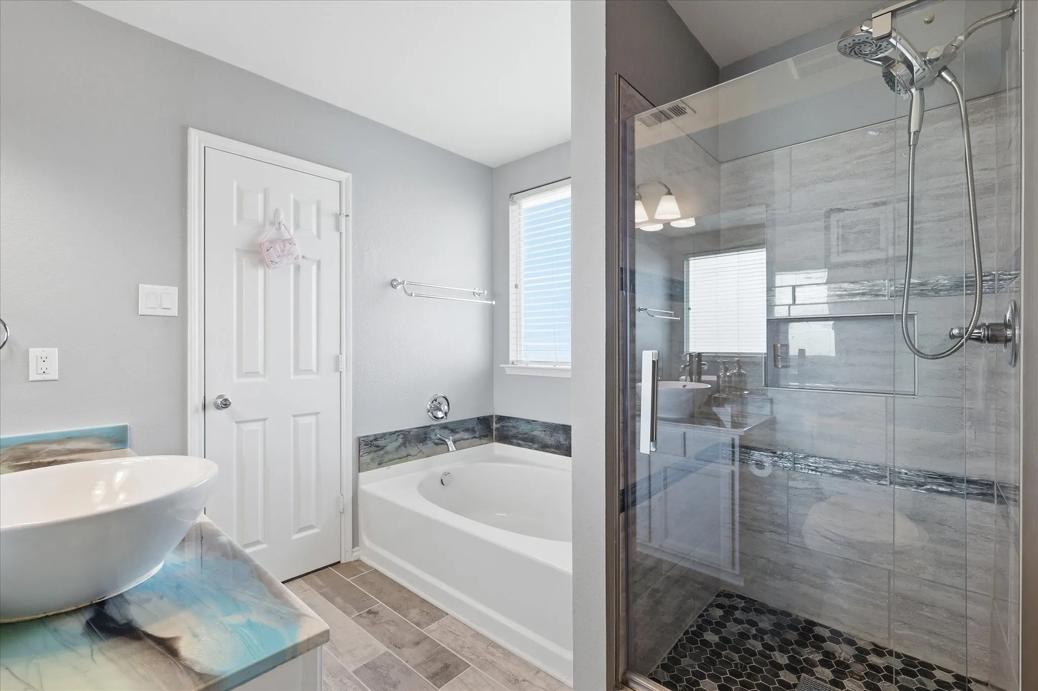 Glass-enclosed shower with a hex tile floor and linear tile walls