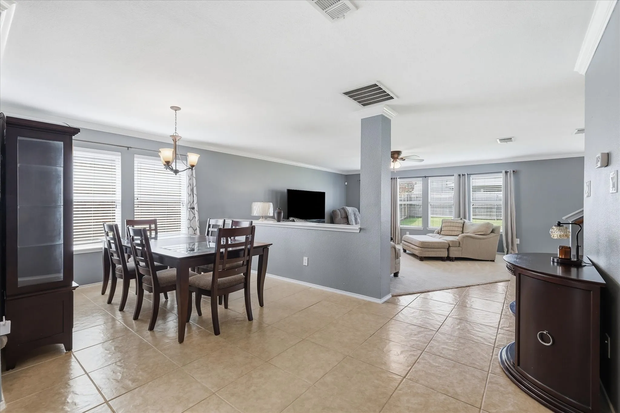 Dining area featuring tile flooring, a multi-light chandelier, and multiple windows with blinds