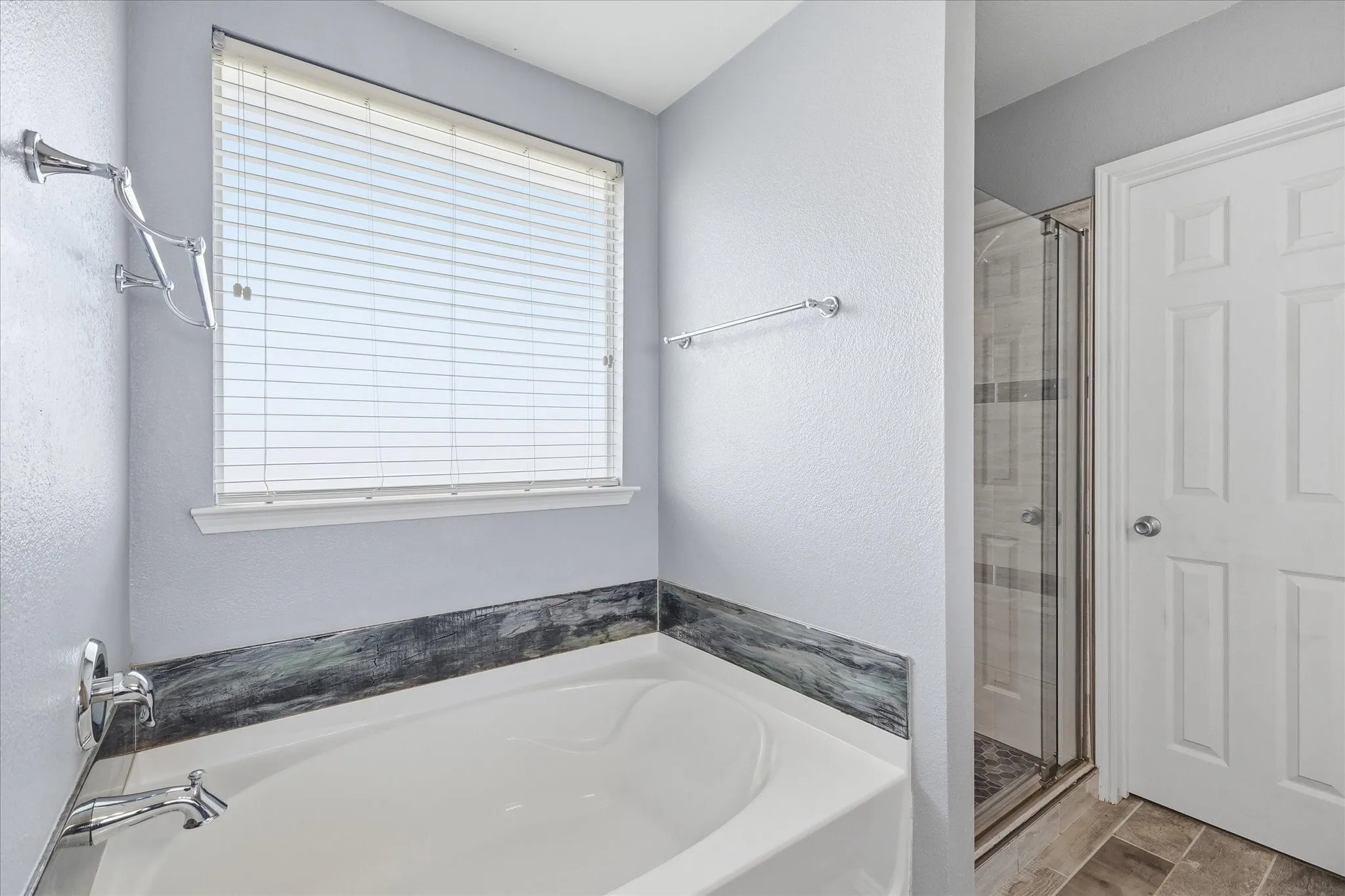 Soaking tub featuring chrome fixtures and a dark stone-look surround