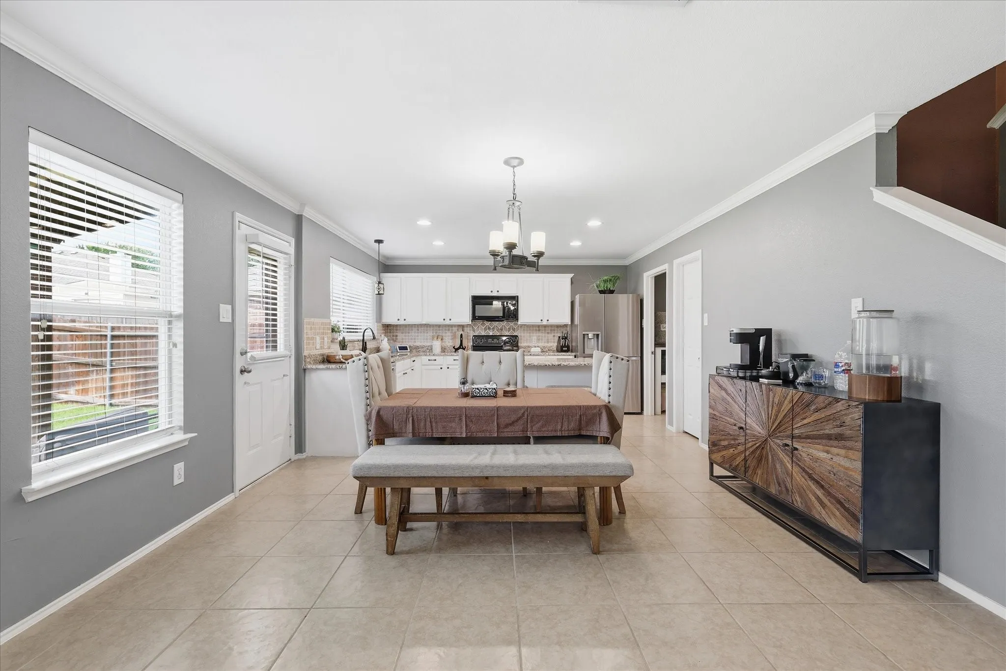 Open-concept living space featuring neutral tile flooring and crown molding
