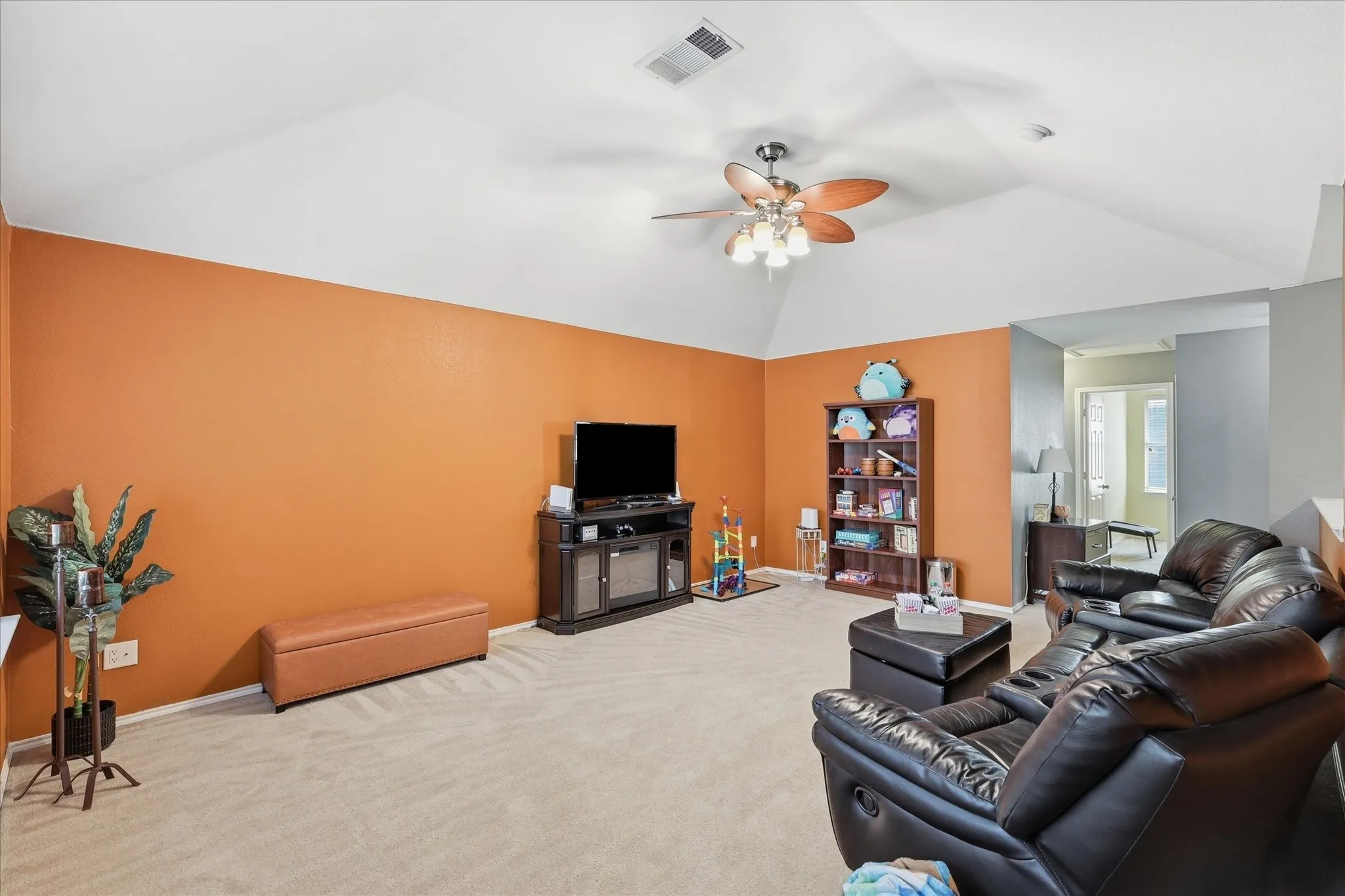 Spacious room featuring vaulted ceilings, a ceiling fan with light fixture, and plush carpet flooring