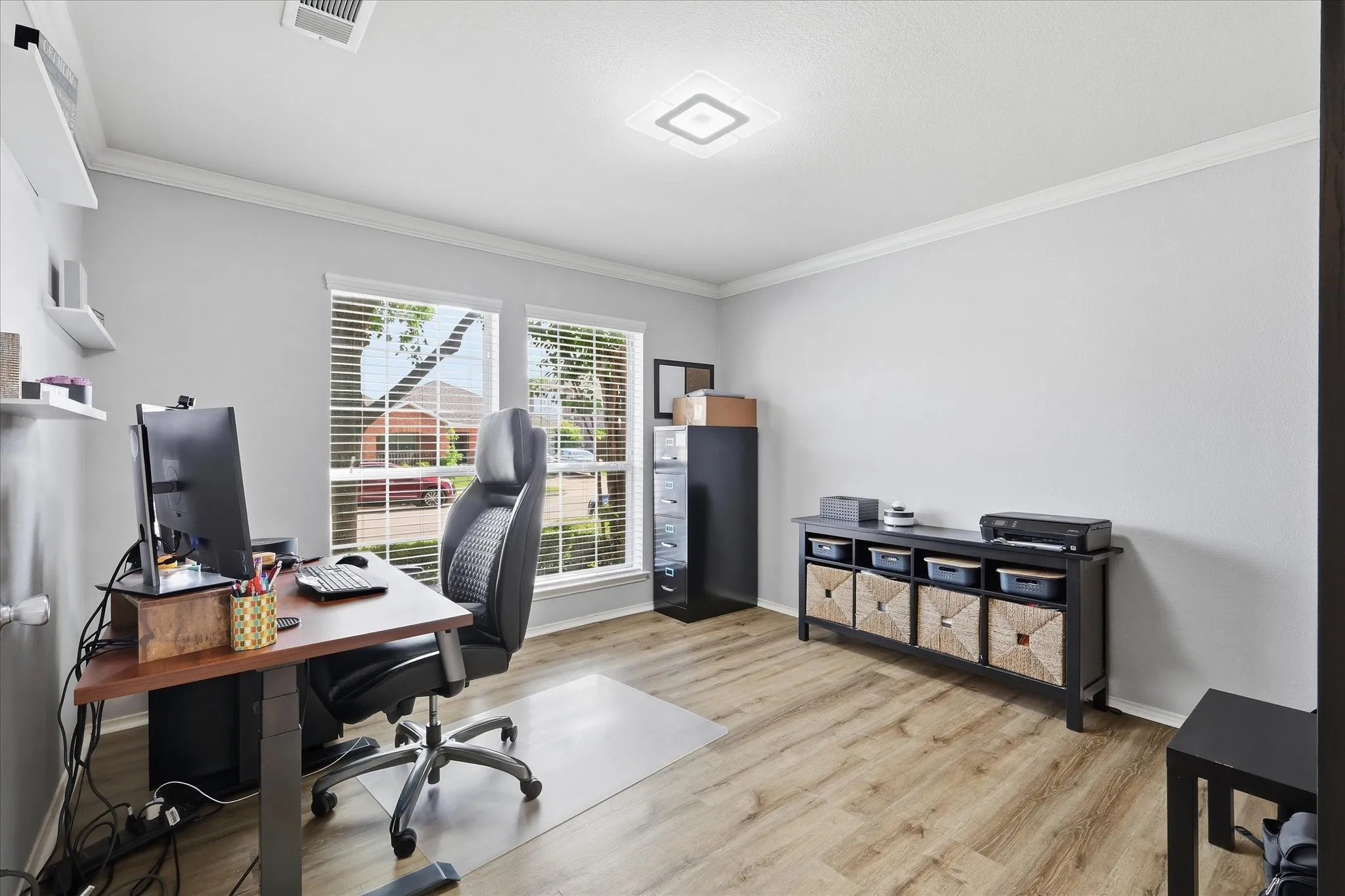 Spacious, private home office featuring french doors, wood-finish flooring, two large windows with blinds, crown molding, and a modern ceiling light fixture