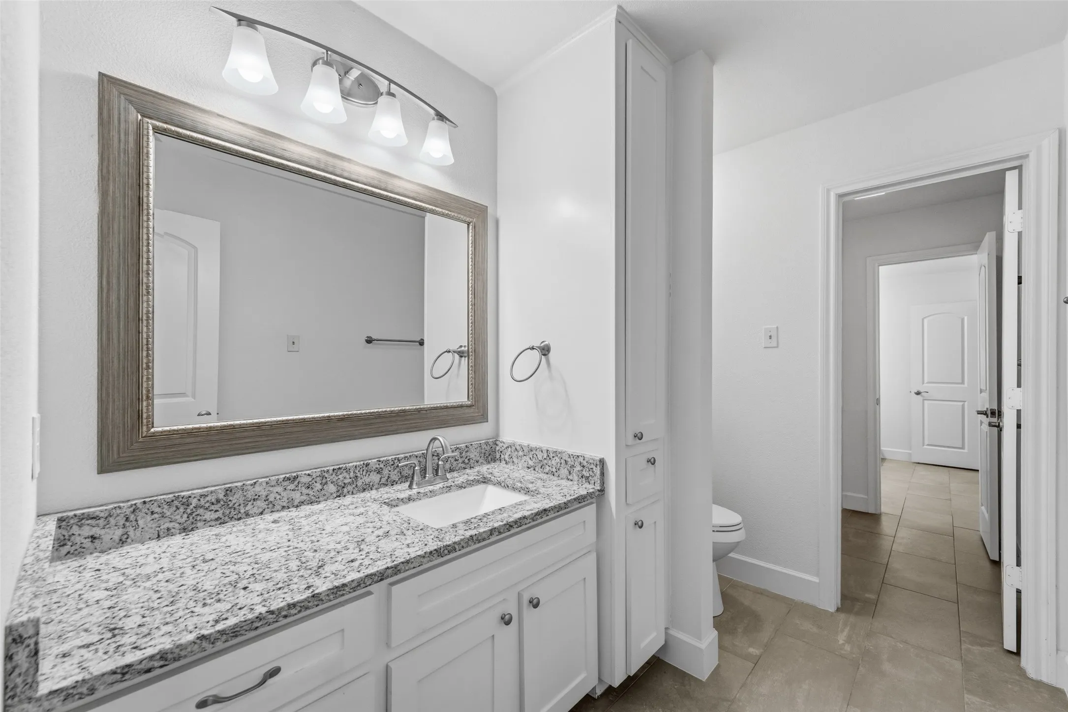 Bathroom vanity featuring a light-toned granite countertop, undermount sink, and brushed nickel faucet