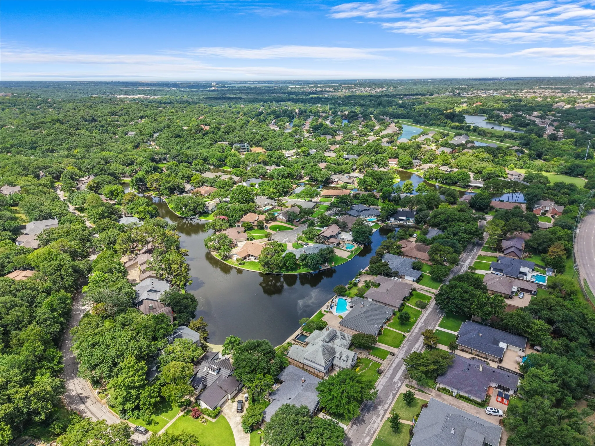 Aerial perspective showcasing a residential community with abundant mature trees and multiple bodies of water