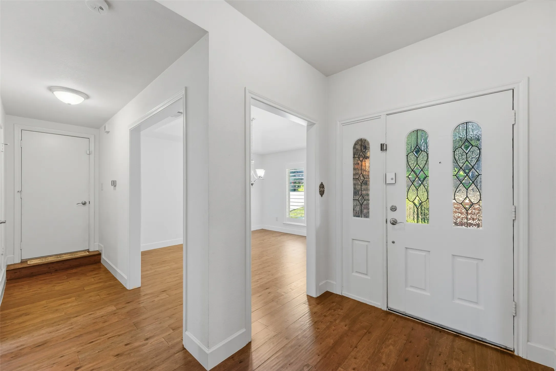 Entryway featuring double doors with decorative glass inserts, wood-finish flooring, and white painted walls