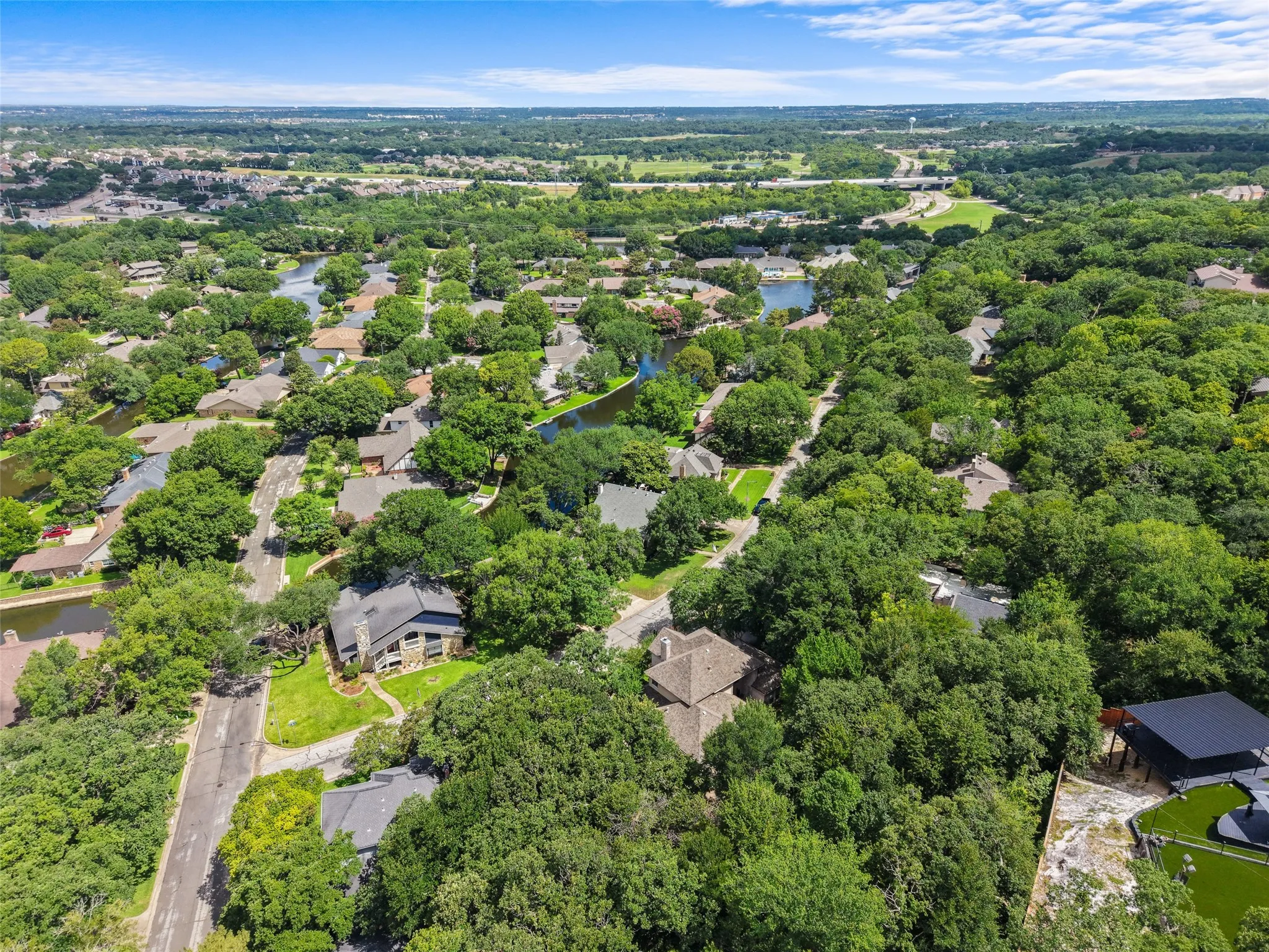 Aerial perspective showcasing a residential neighborhood with extensive tree canopies, numerous homes, and visible waterways