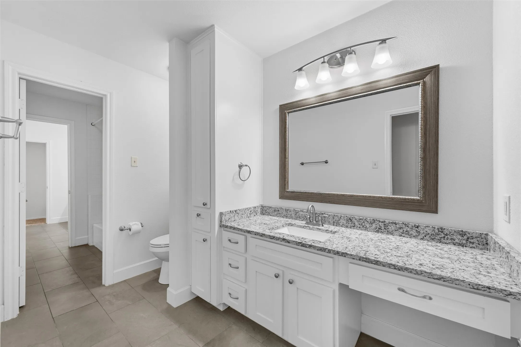 Bathroom featuring a spacious vanity with a light-toned countertop, an undermount sink, and white cabinetry