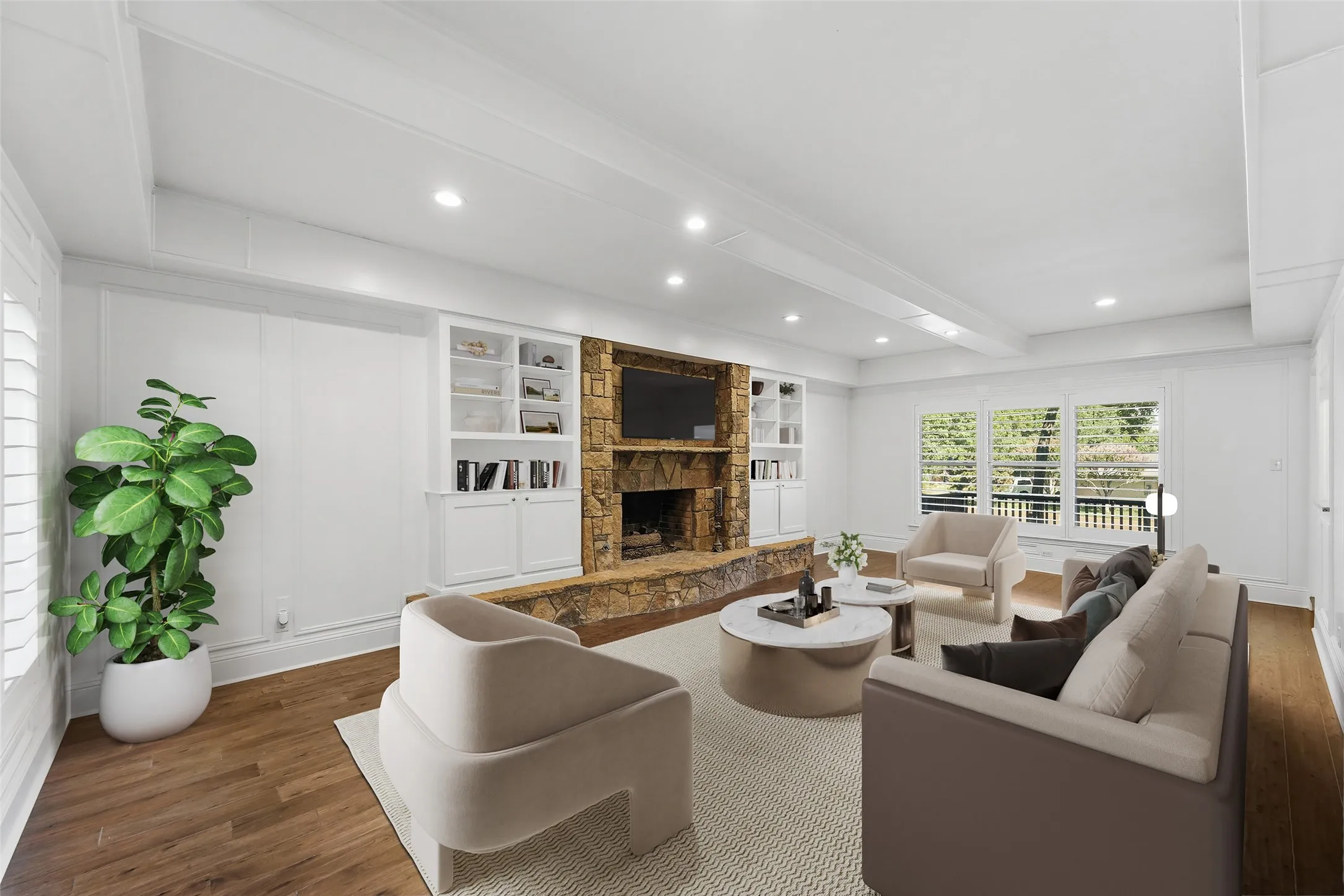 Living area featuring a stone fireplace with hearth, built-in shelving, wood-finish flooring, recessed lighting, and multiple windows with plantation shutters