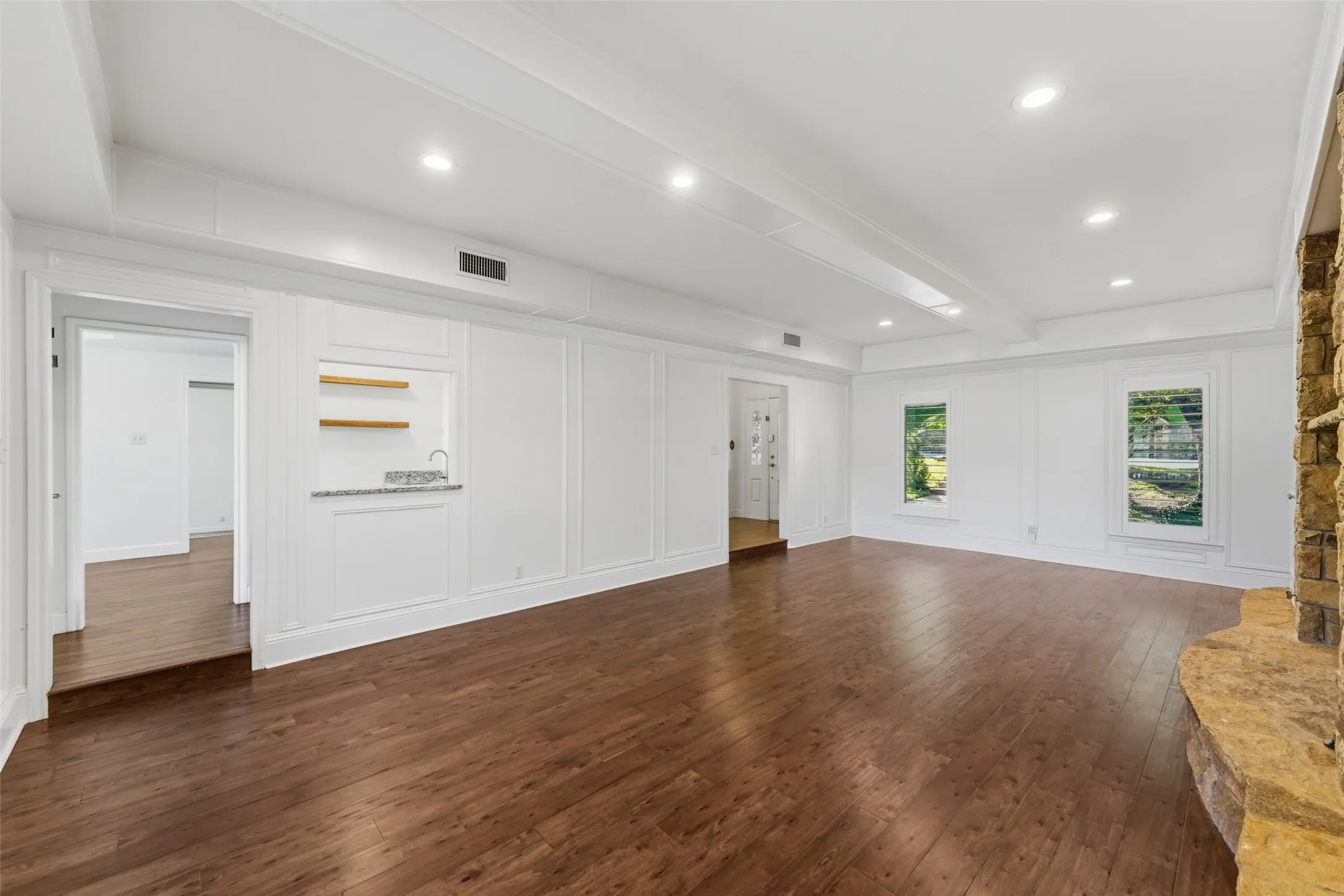 Spacious room featuring wood-finish flooring, recessed lighting, and white paneled walls