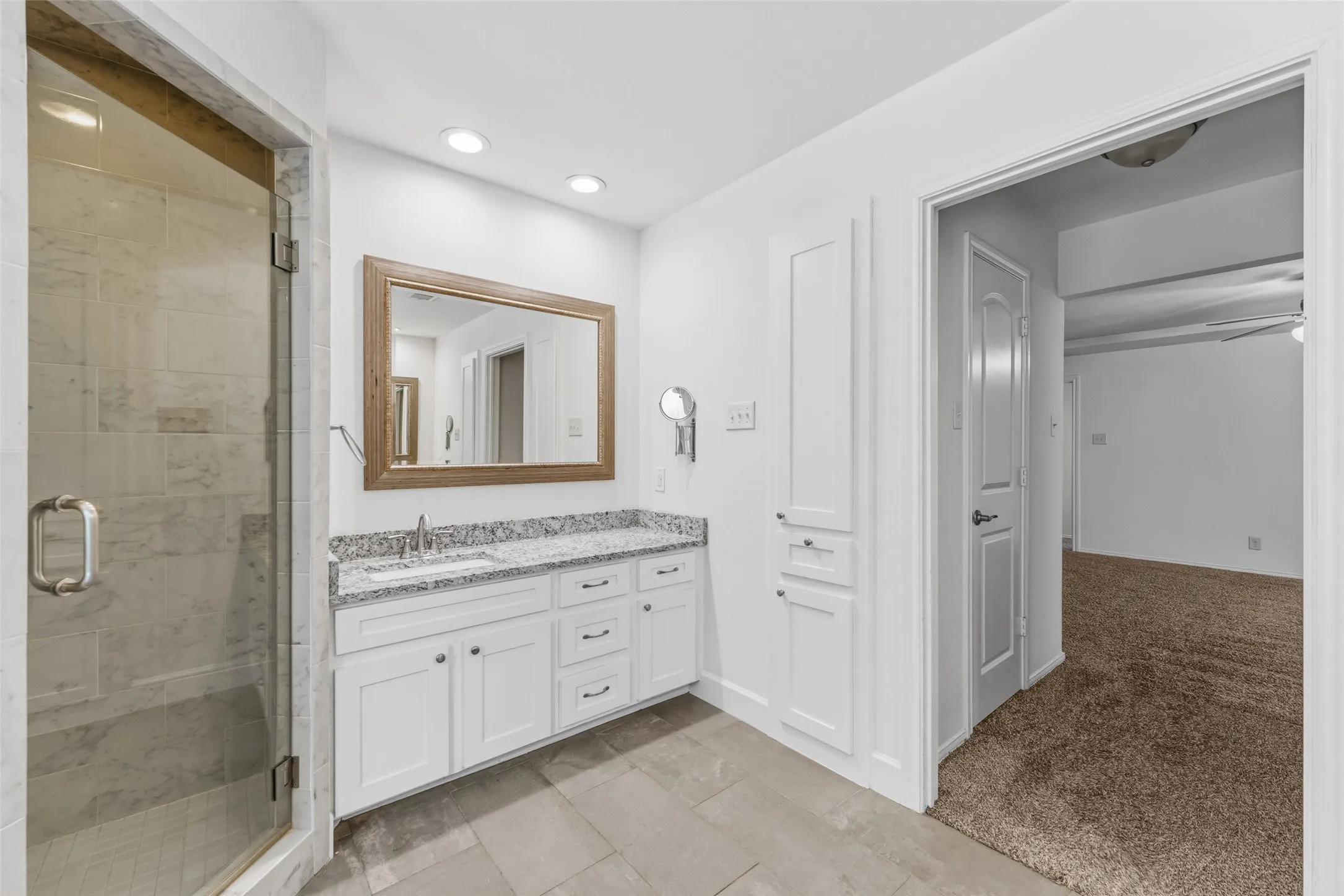 Bathroom featuring a frameless glass shower, white vanity with granite-style countertop, rectangular undermount sink, built-in storage cabinet, and recessed lighting
