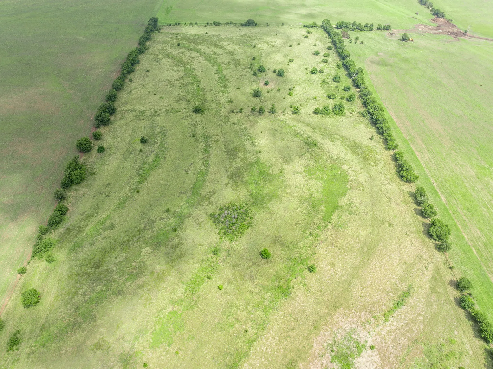 Expansive rural acreage featuring a large, open field of grass and scattered mature trees