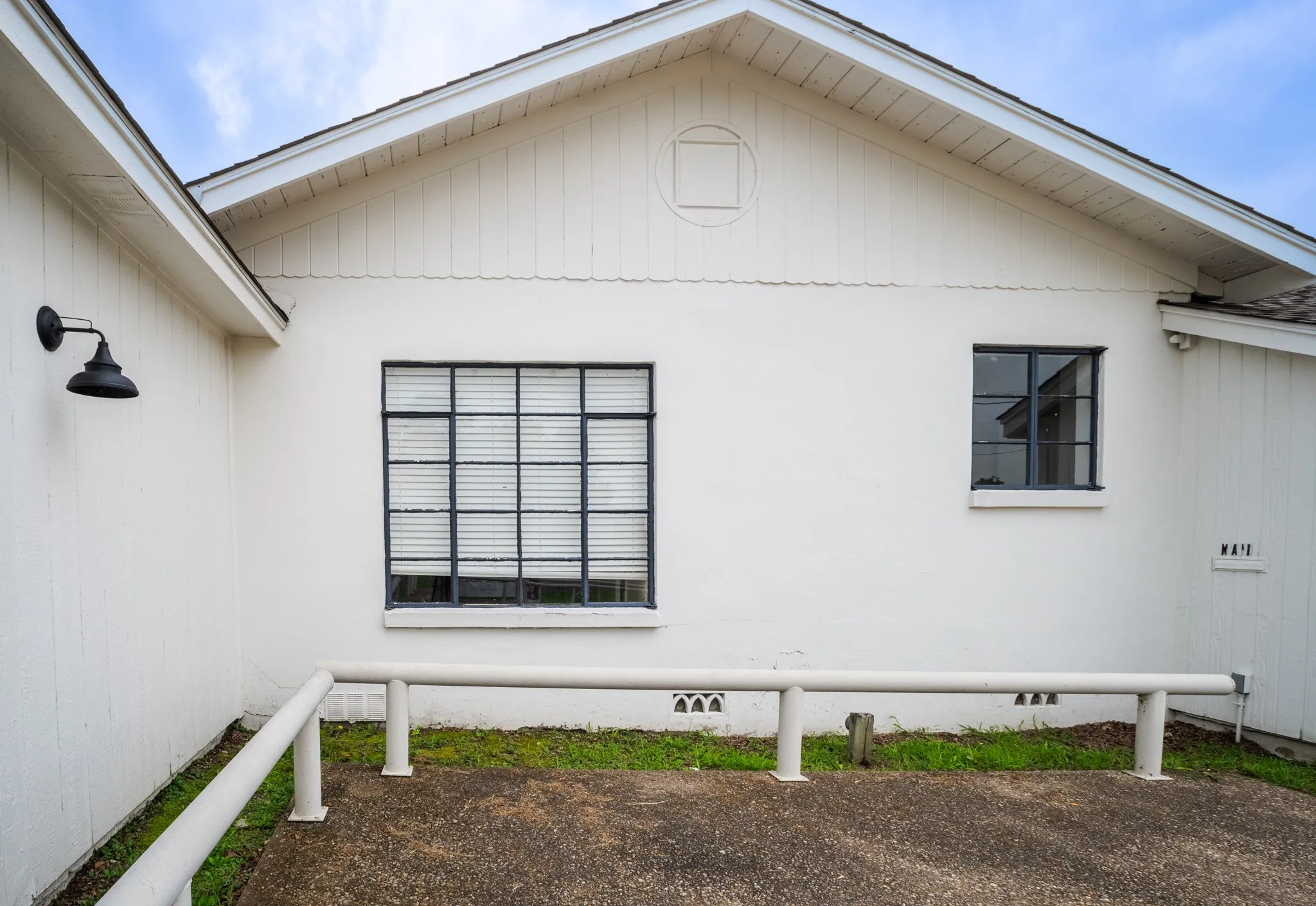 White exterior wall with contrasting black-framed windows and a black exterior sconce