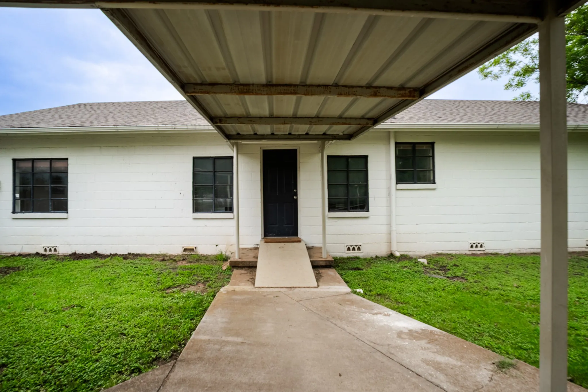 White brick exterior featuring a dark entry door and black-framed windows
