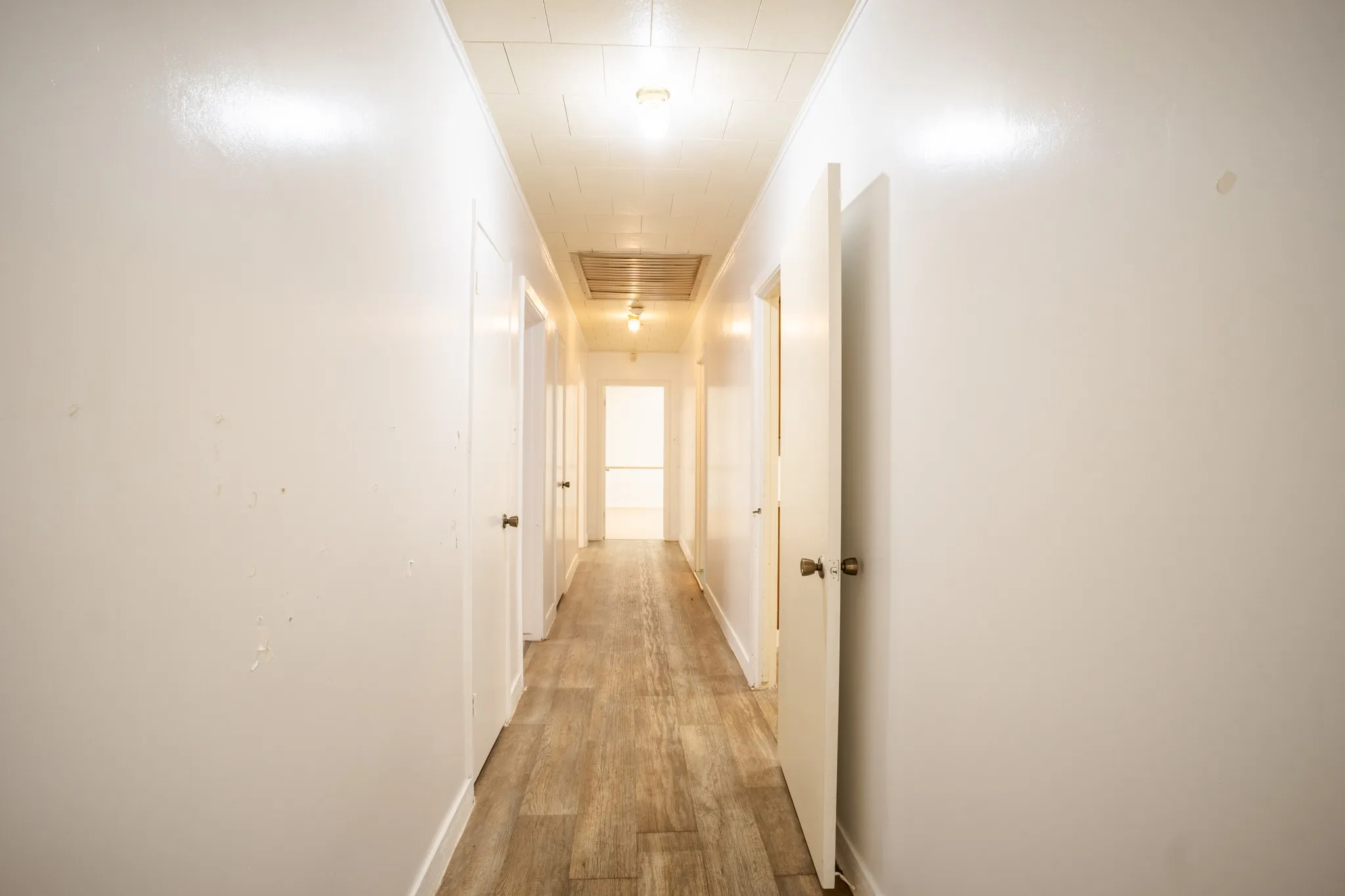 Hallway featuring wood-finish flooring, white walls, and white trim