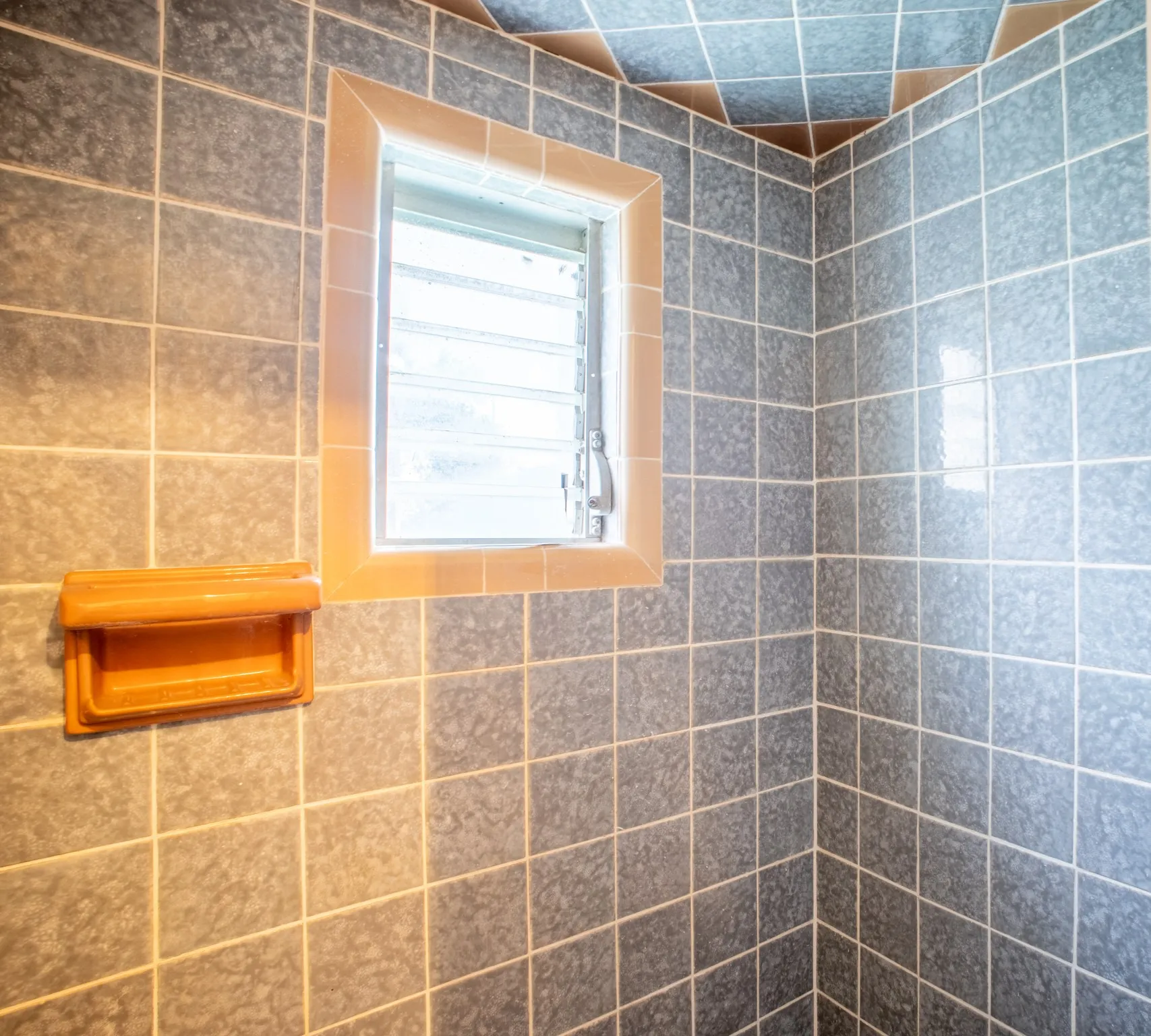 Bathroom featuring square slate-look wall tiles with contrasting grout