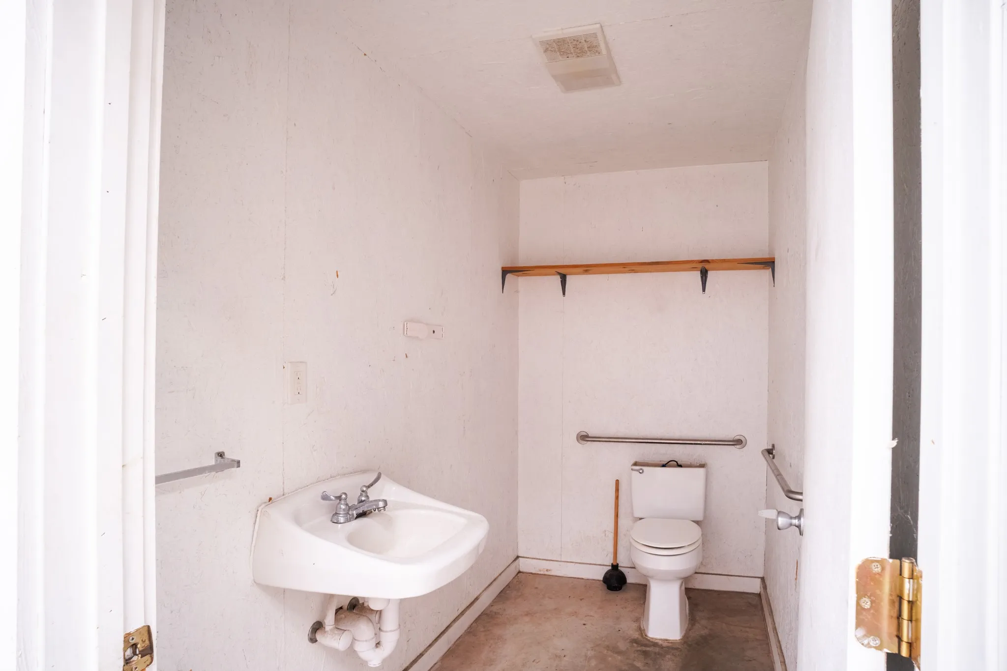 Compact powder room featuring a wall-mounted sink, a toilet, and dual grab bars