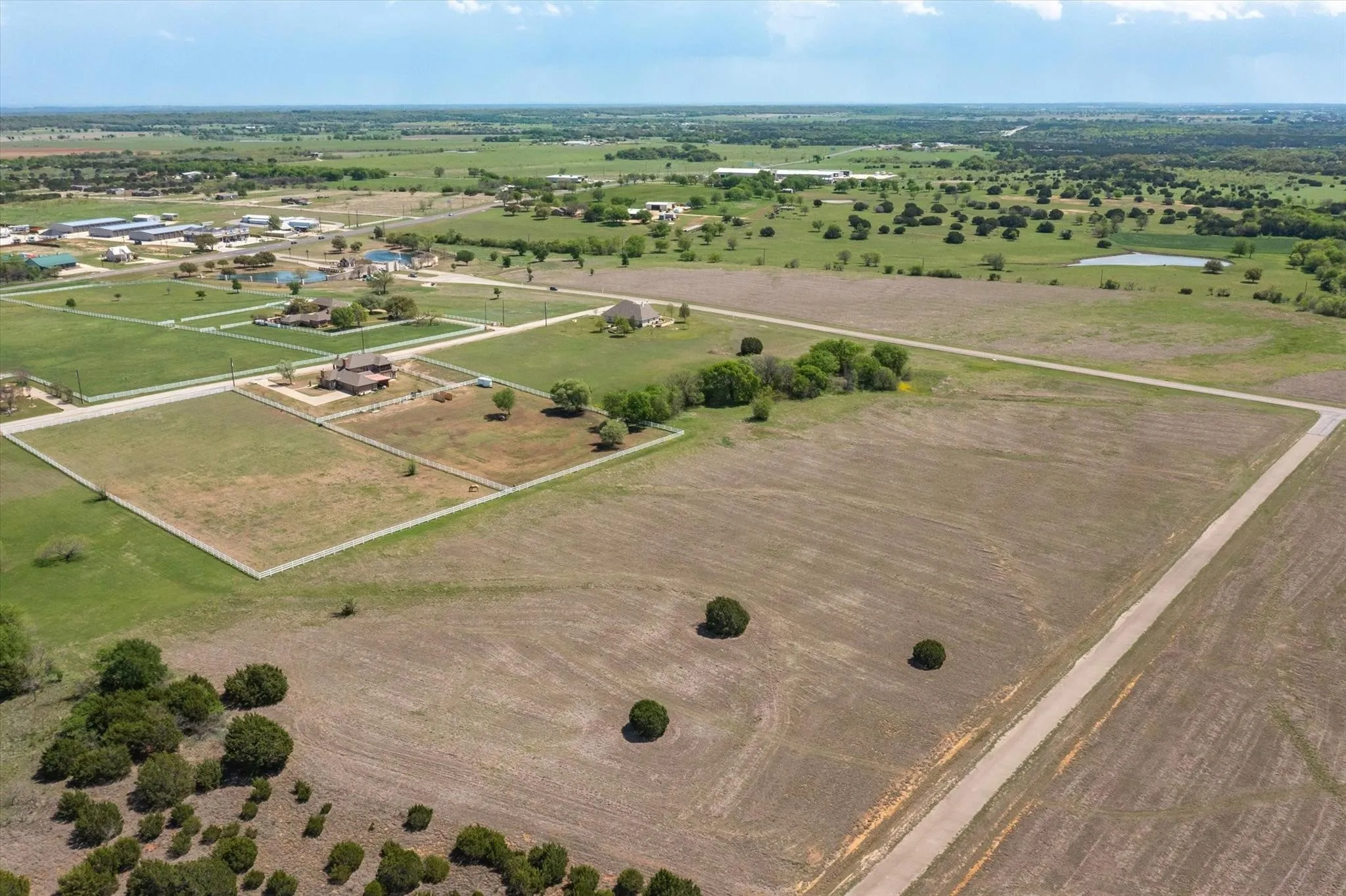 Expansive land parcel featuring open fields, scattered mature trees, and existing access roads