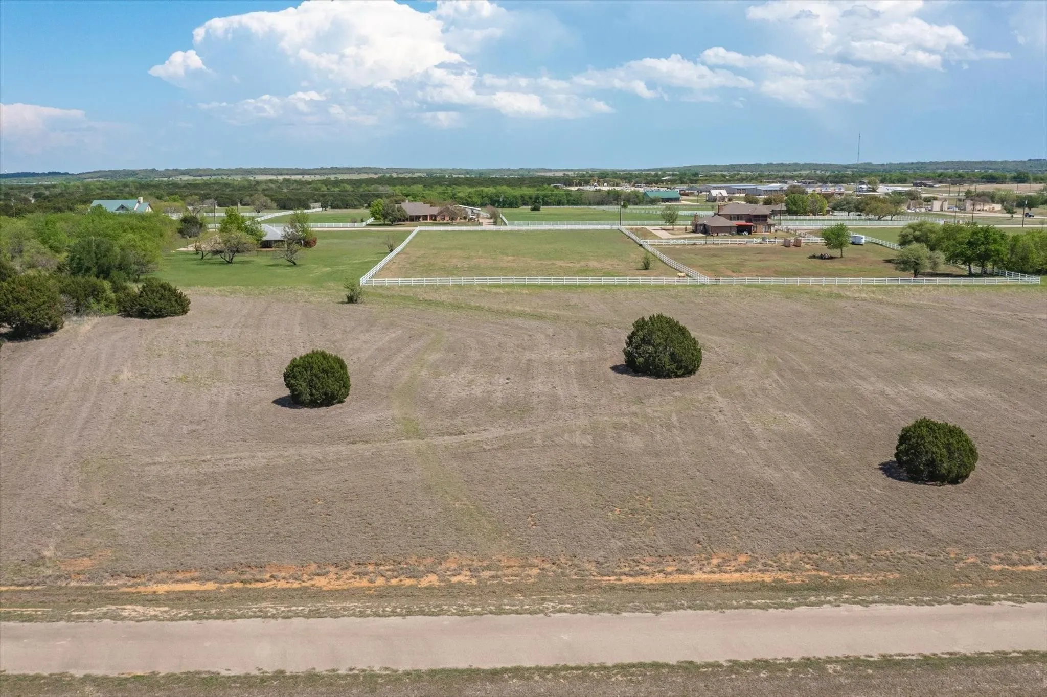 Expansive undeveloped land parcel featuring mature landscaping and a perimeter fence