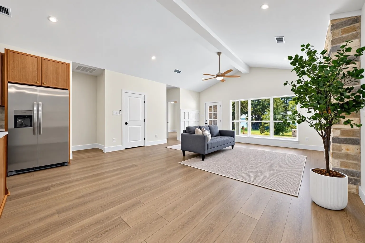 Vaulted ceiling with exposed beam, wood-finish flooring, recessed lighting, and a modern ceiling fan