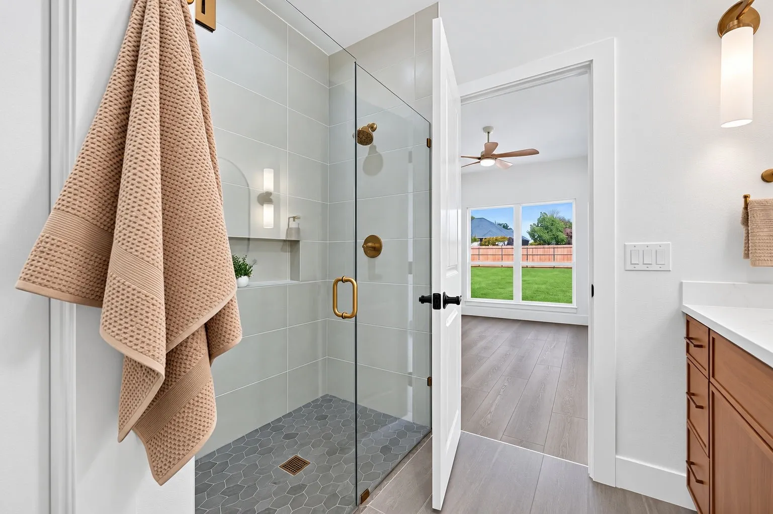 Glass-enclosed shower with gold-tone fixtures and tiled walls