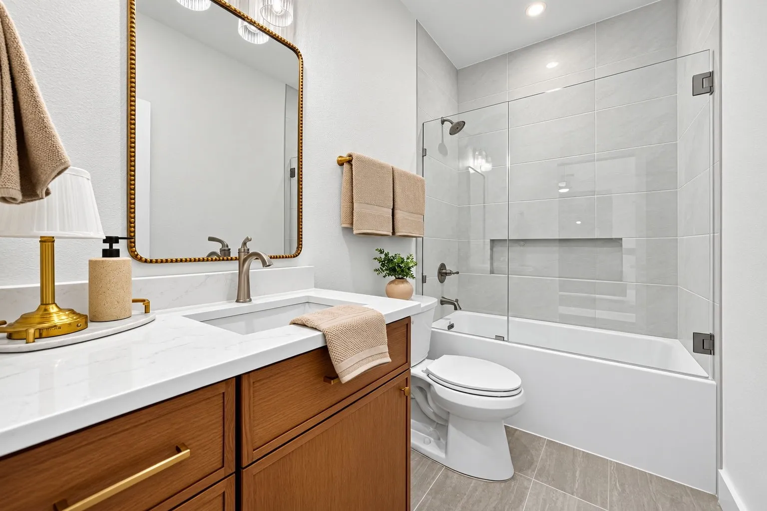 Wood-finish vanity with gold-tone hardware, rectangular undermount sink, and a white countertop