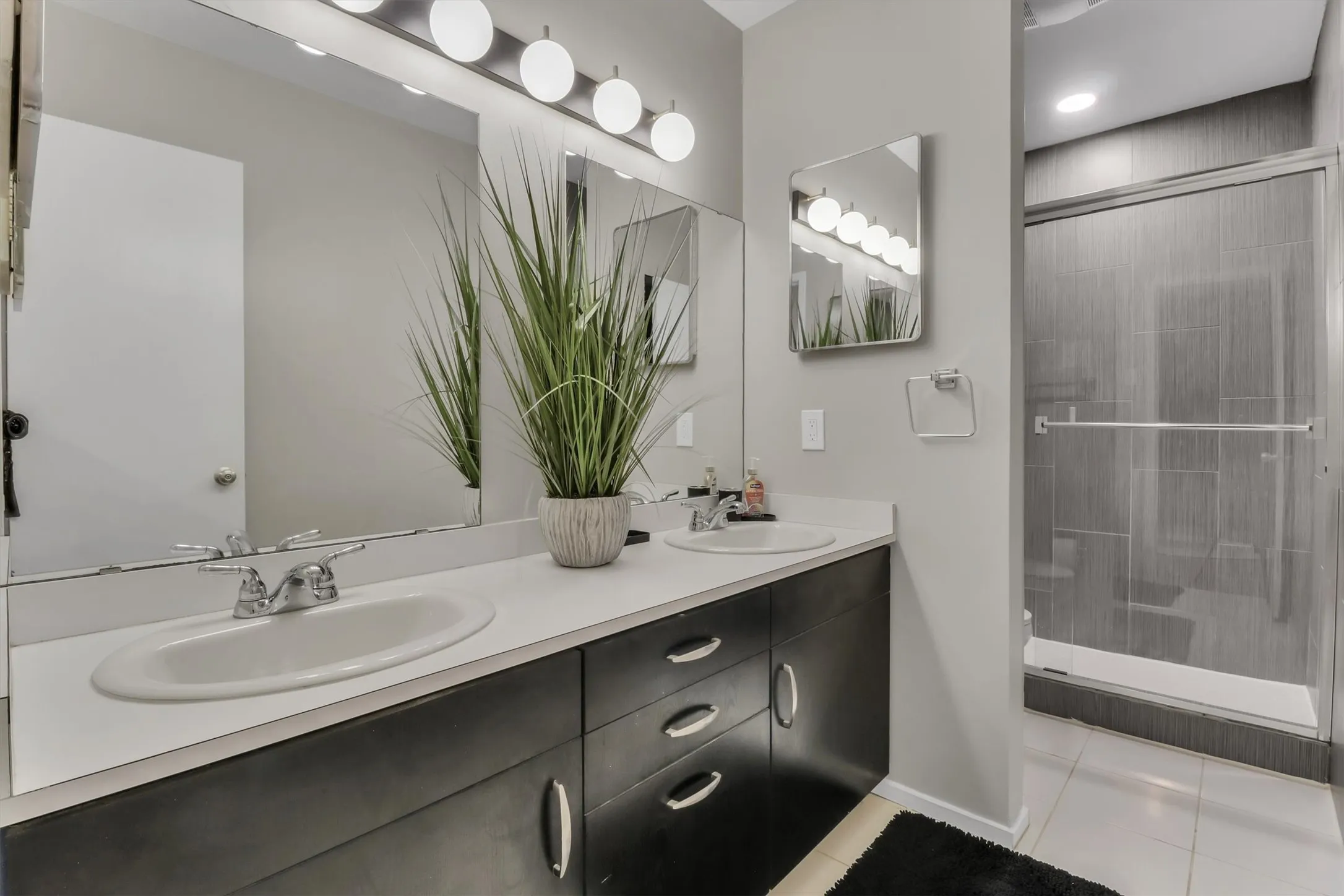 Bathroom featuring a dual vanity with white countertops and dark wood-finish cabinetry
